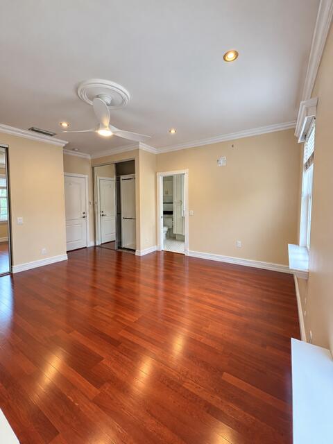 Wood-finish flooring, recessed lighting, crown molding, ceiling fan with decorative medallion, and mirrored sliding closet doors