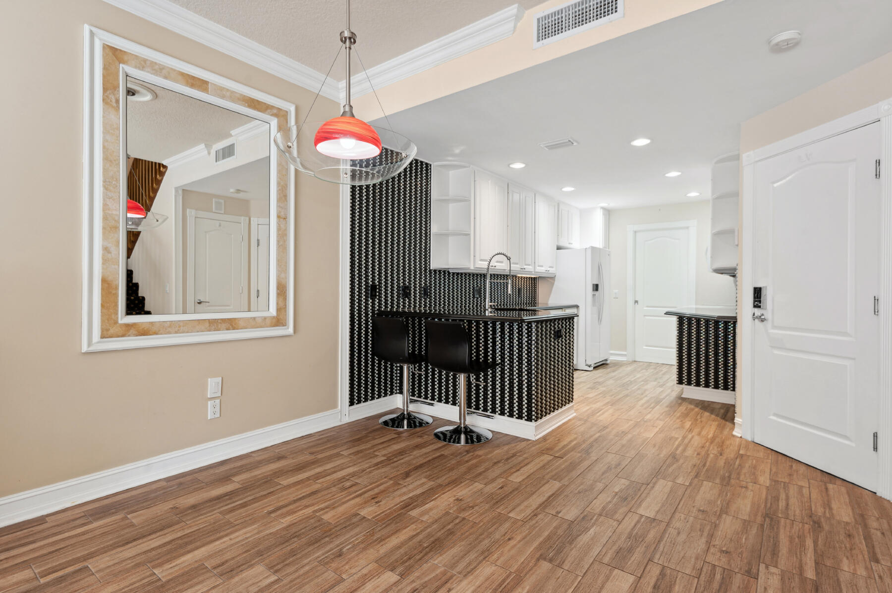 Kitchen featuring wood-finish flooring, white cabinetry, dark countertops, a breakfast bar with decorative tile detailing, and recessed lighting