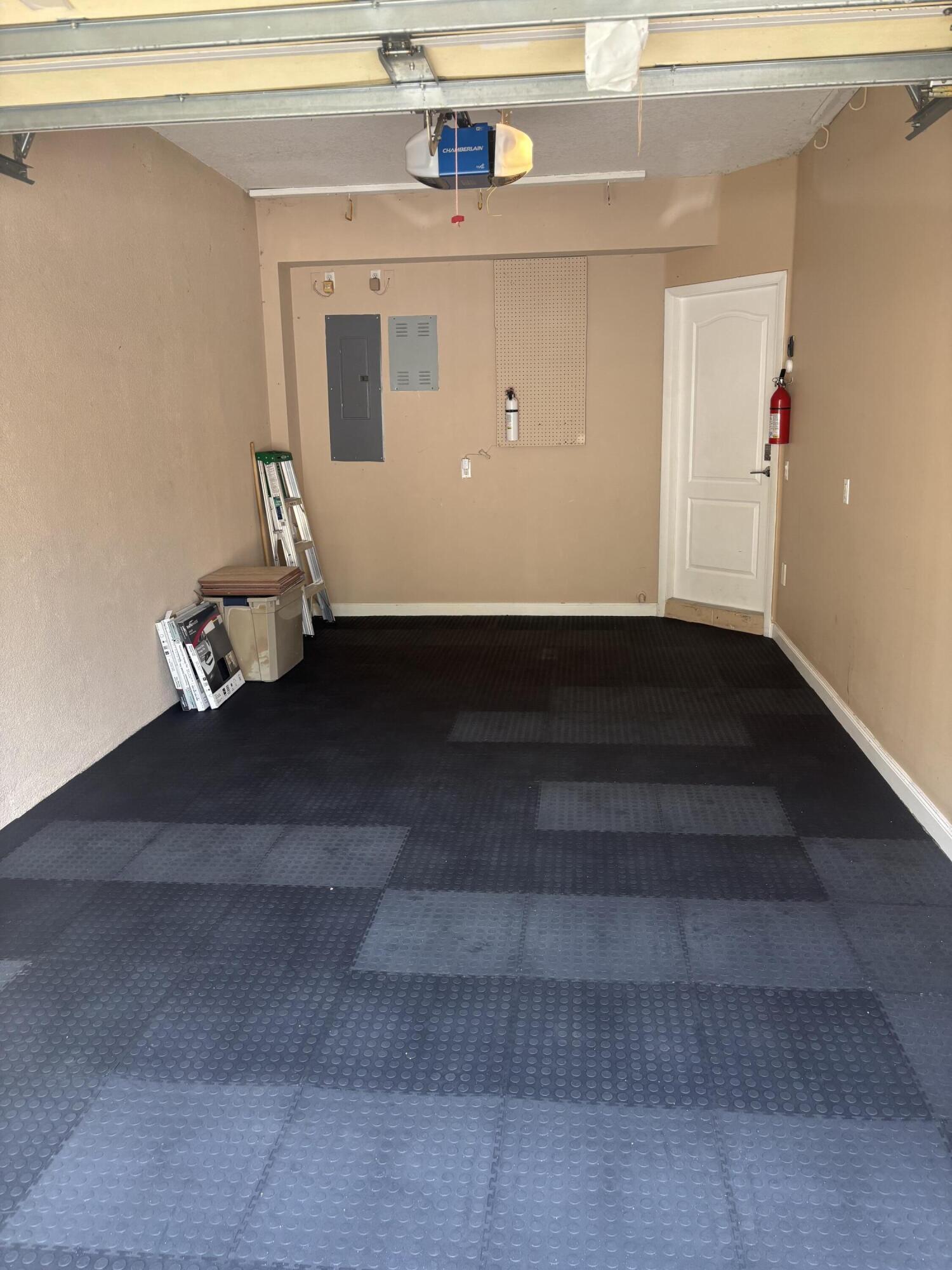 Garage interior featuring modular rubberized flooring, an automated overhead door opener, and a panel-style interior door