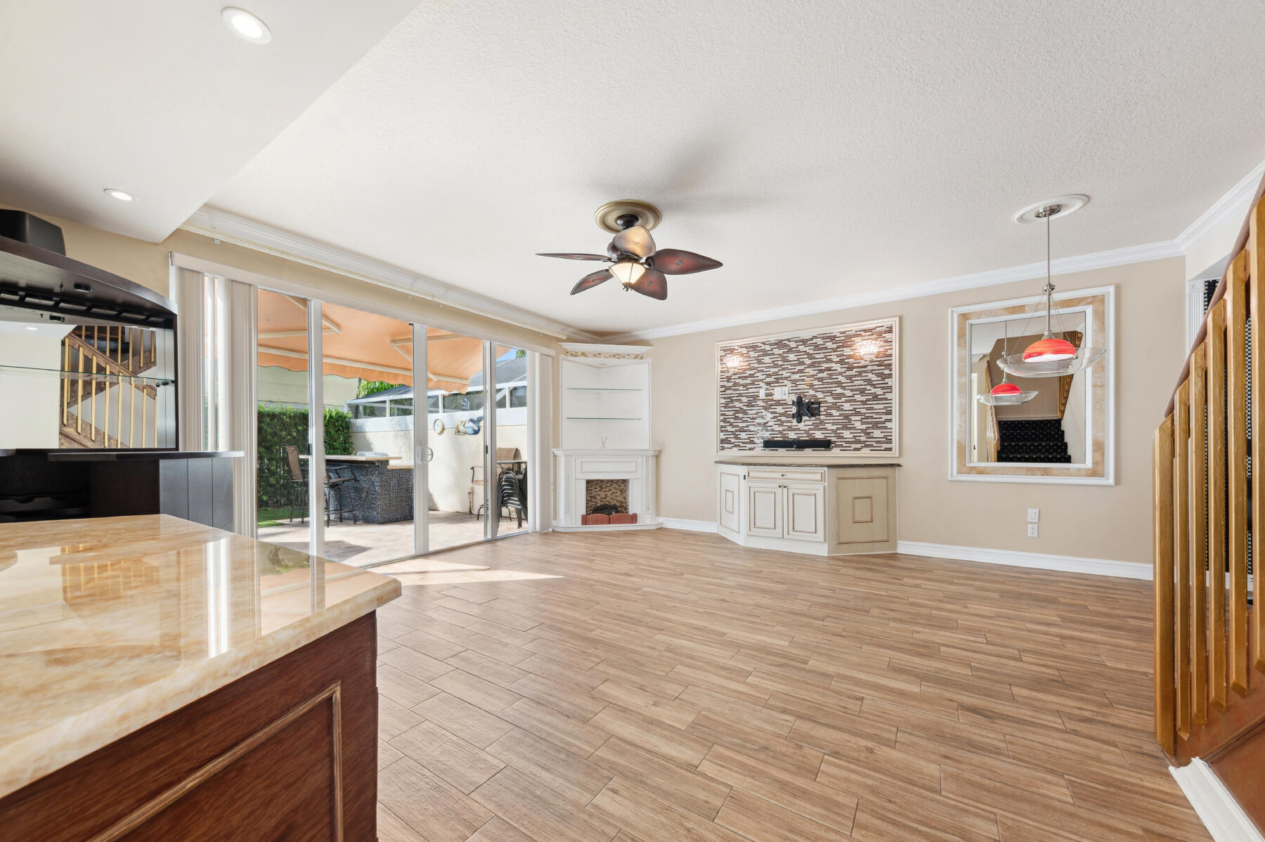 Wood-finish tile flooring, sliding glass doors, corner built-in shelving, custom cabinetry with a stone-finish accent wall, and recessed lighting