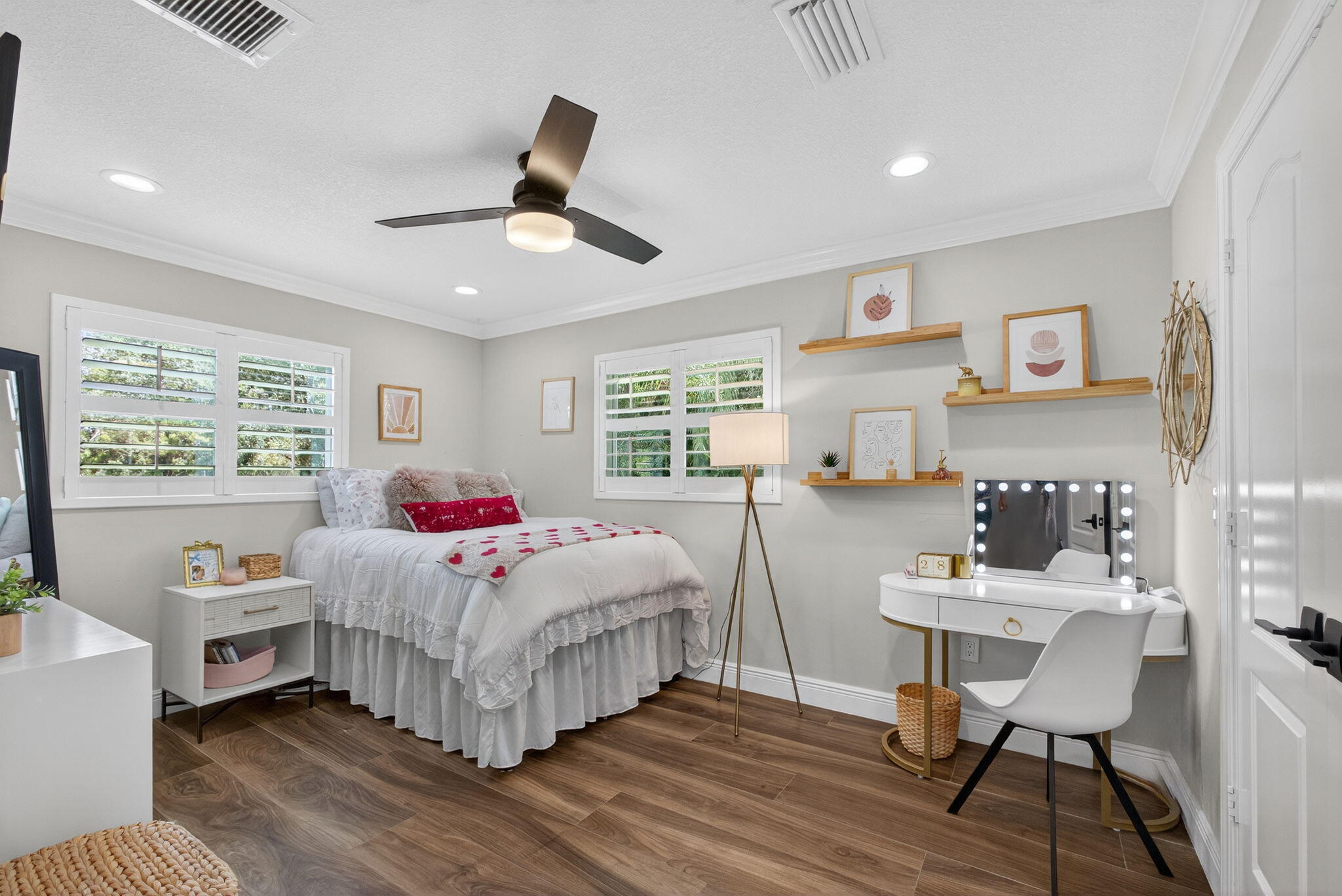 Neutral-toned room featuring wood-finish flooring, plantation shutters, recessed lighting, a modern ceiling fan, and built-in wall shelving