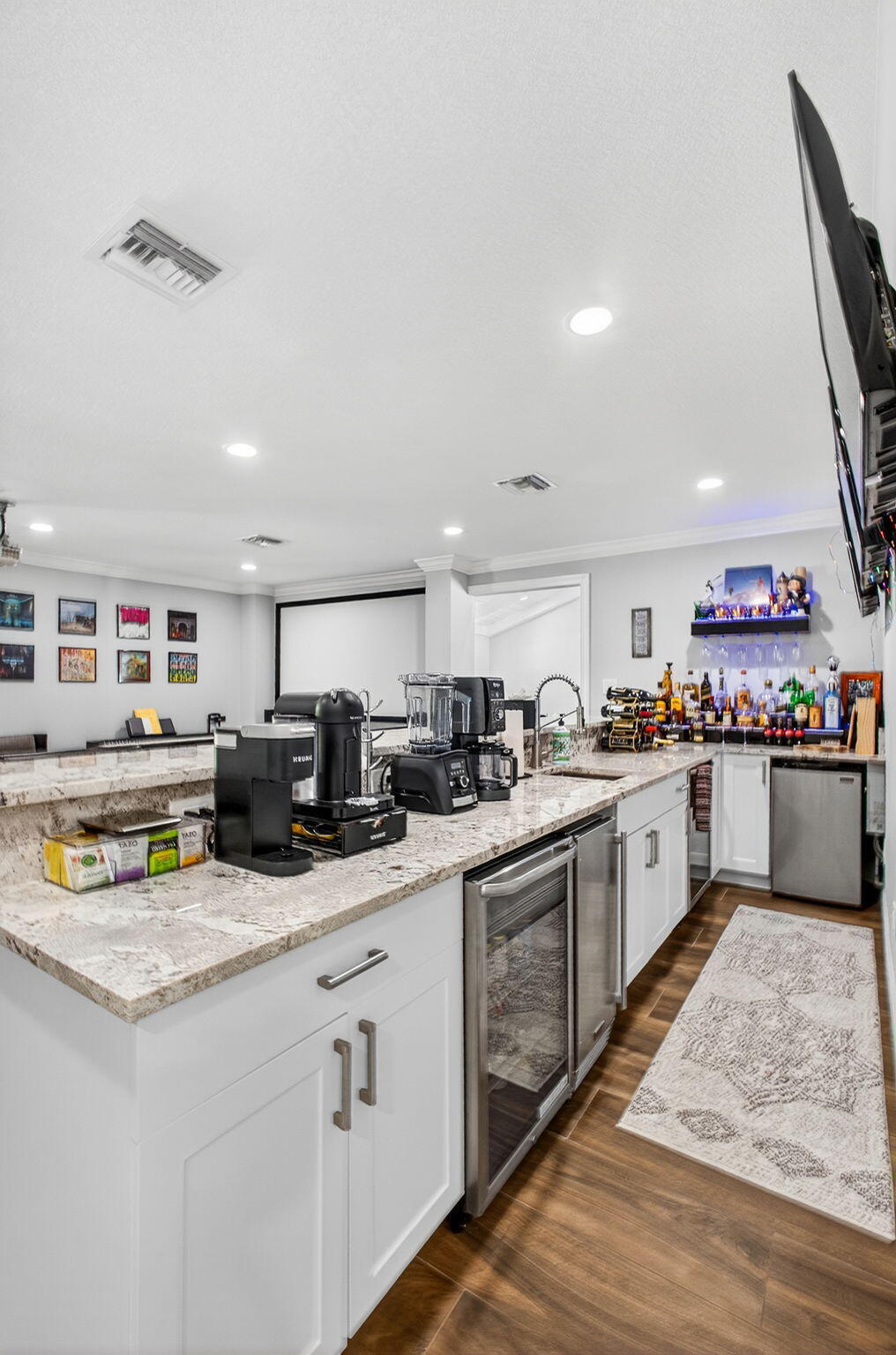 Wet bar featuring white cabinetry, stone countertops, stainless steel under-counter appliances, recessed lighting, and wood-finish flooring