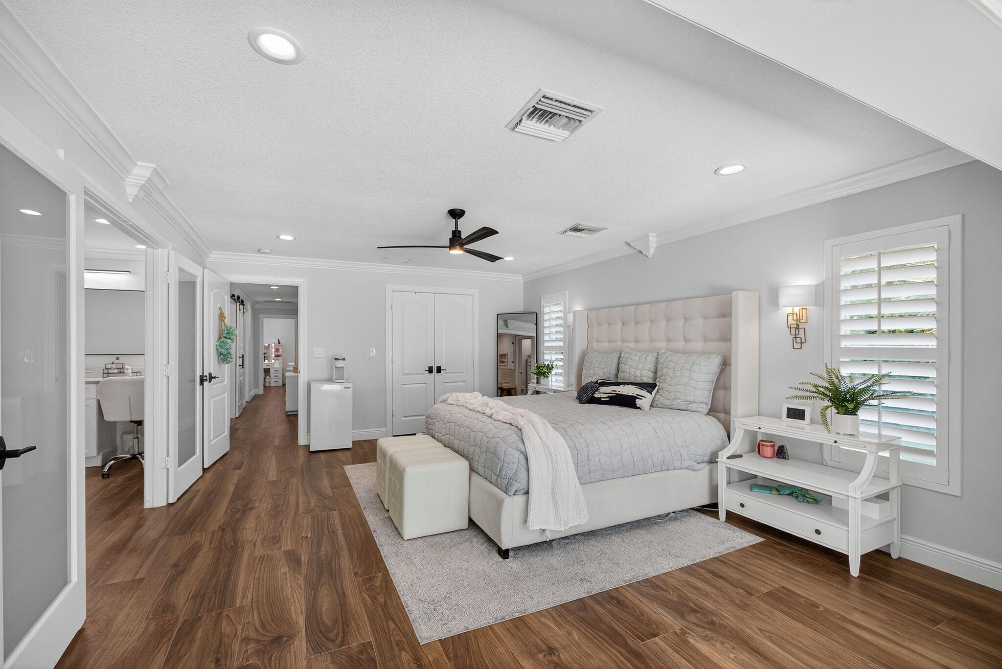 Spacious room featuring wood-finish flooring, recessed lighting, crown molding, plantation shutters, and a ceiling fan