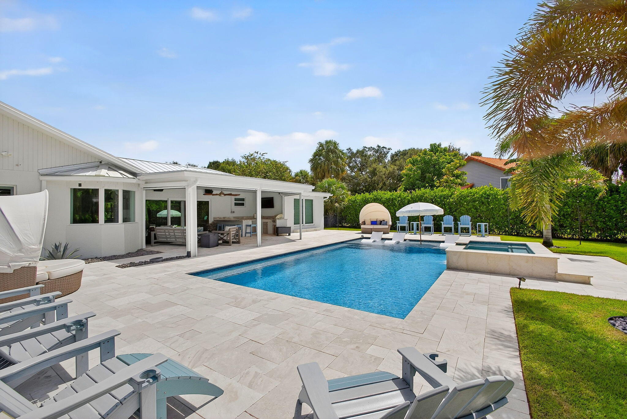 Outdoor living area featuring a covered patio, a rectangular swimming pool, an elevated integrated spa, stone-paver decking, and manicured landscaping