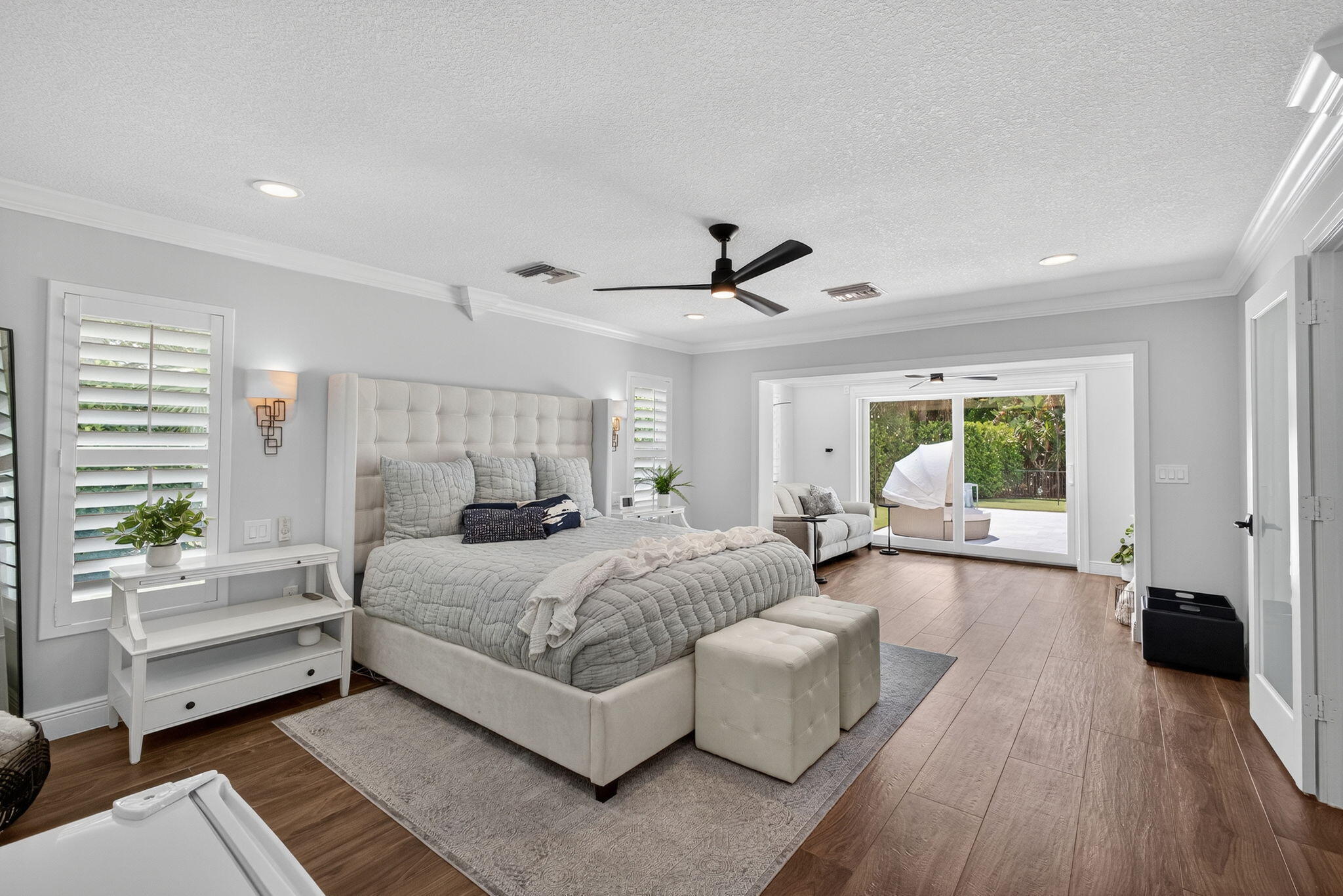 Wood-finish flooring, crown molding, recessed lighting, ceiling fan with integrated light, and sliding glass doors