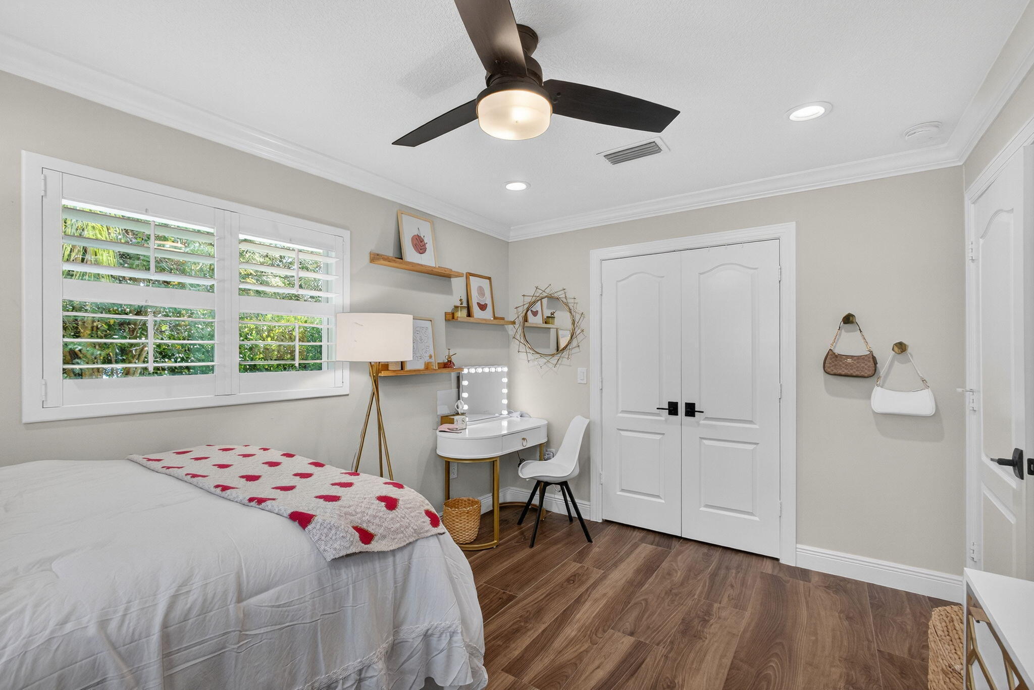 Room featuring wood-finish flooring, plantation shutters, a ceiling fan with integrated lighting, recessed lighting, and double doors with matte black hardware