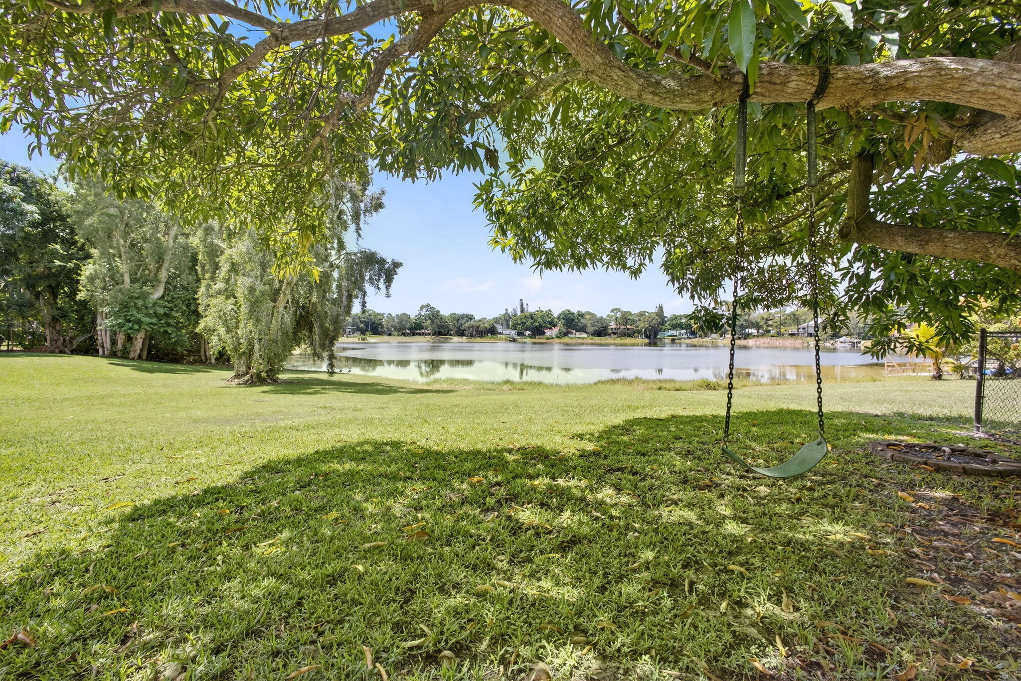 Expansive lawn featuring mature trees and a waterfront border