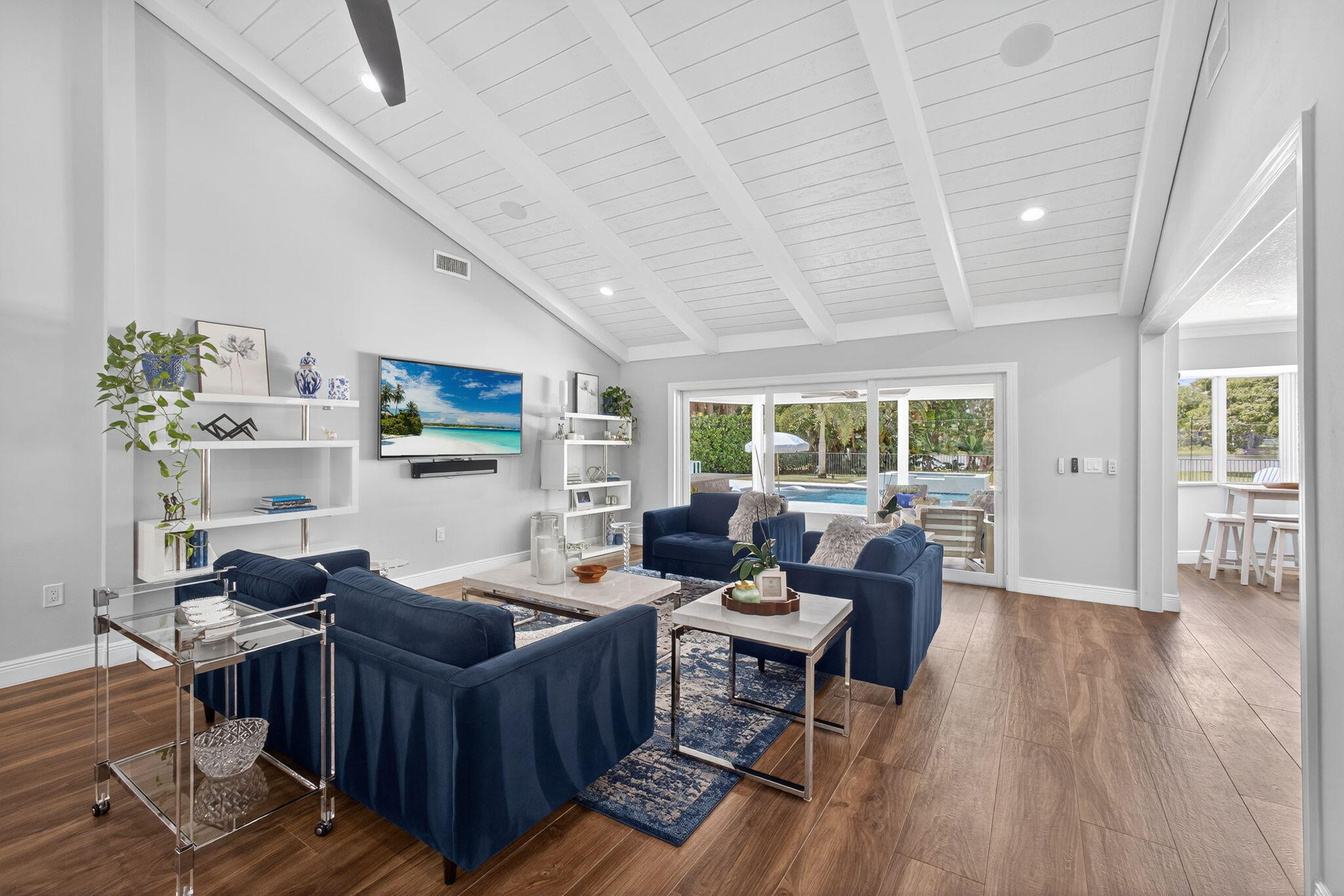 Vaulted ceiling featuring exposed beams and tongue-and-groove paneling, wide-plank wood-finish flooring, built-in shelving, and floor-to-ceiling sliding glass doors