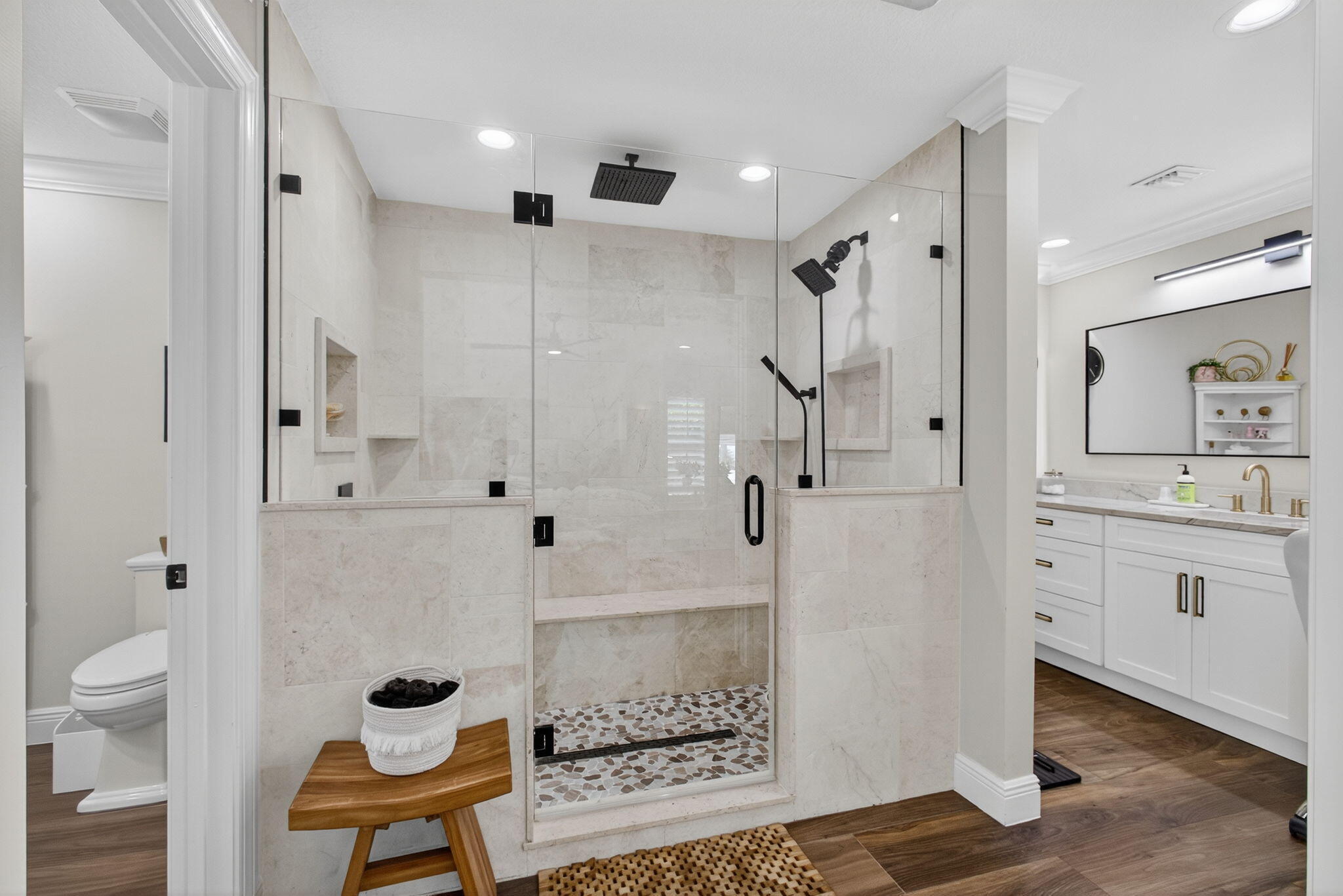 Walk-in shower featuring a glass enclosure, built-in stone bench, overhead rainfall showerhead, and pebble-tile flooring