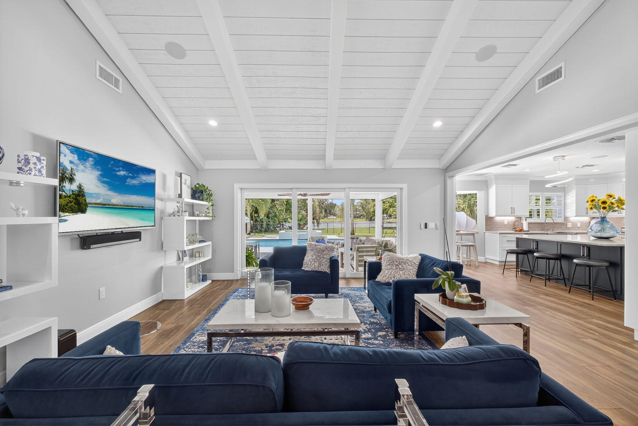 Living area featuring a vaulted tongue-and-groove ceiling with exposed beams, wood-finish flooring, built-in shelving, and floor-to-ceiling sliding glass doors