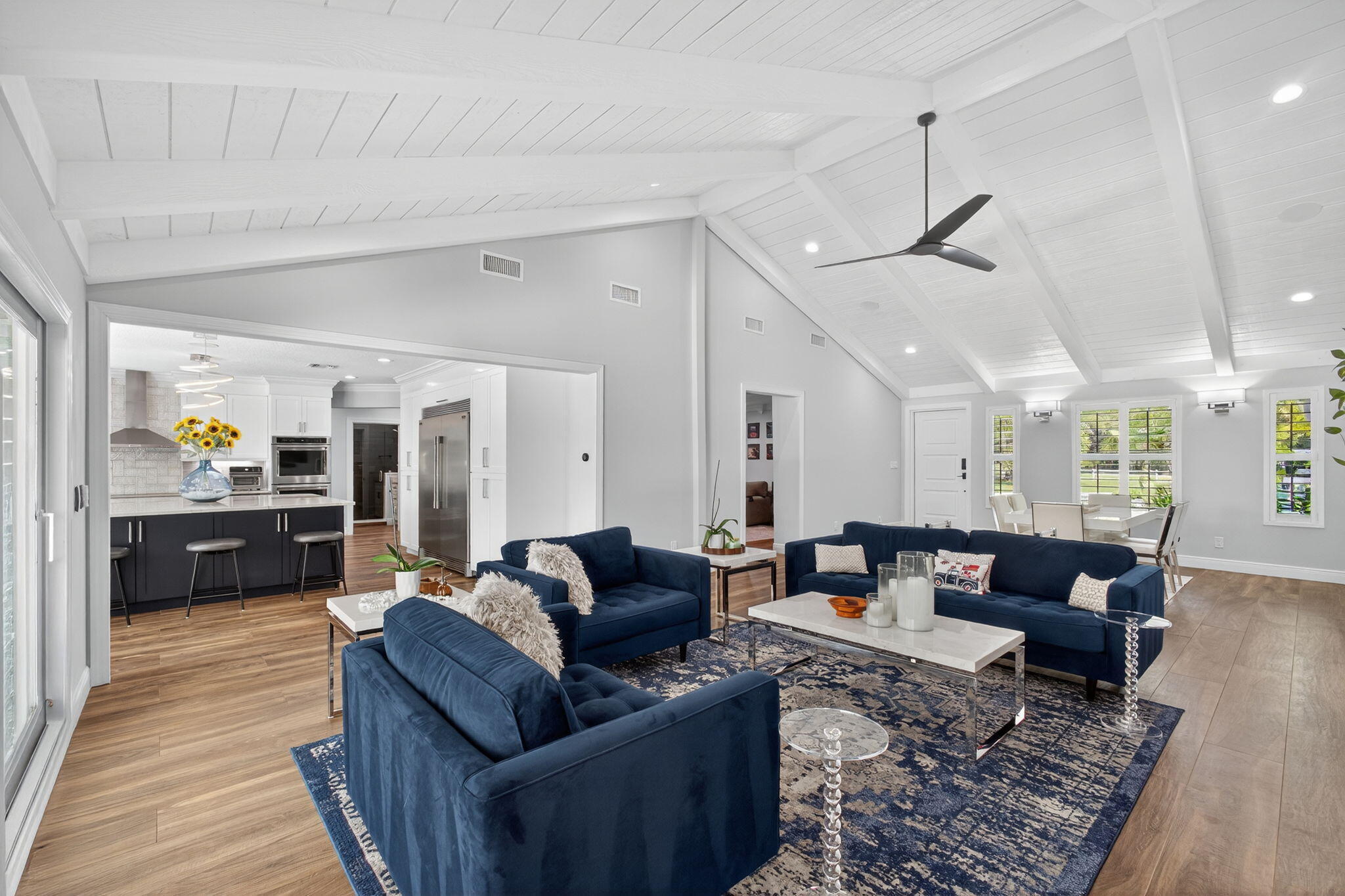 Vaulted ceilings with exposed beams, wood-finish flooring, recessed lighting, and a modern ceiling fan