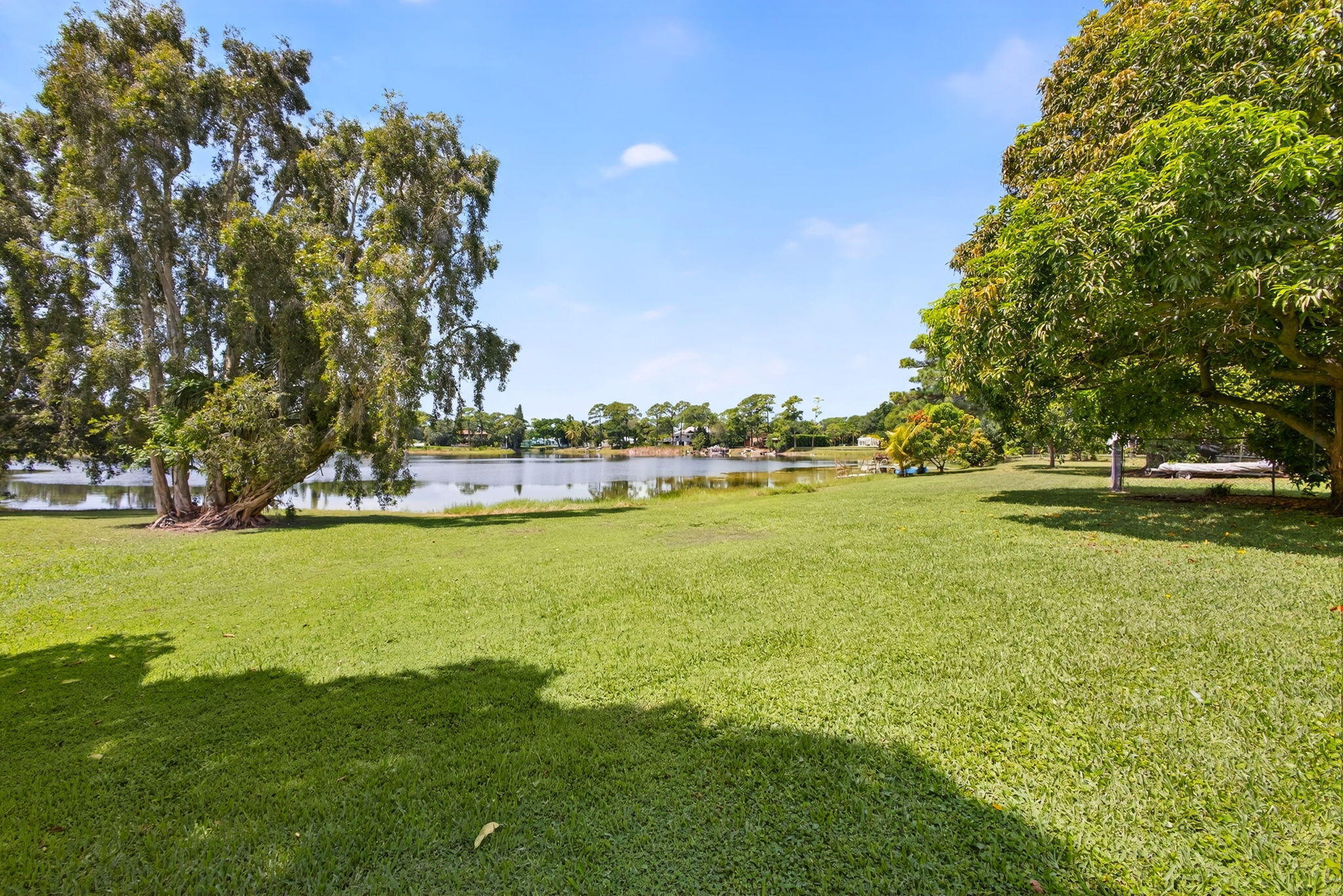 Expansive grassy lawn featuring mature trees and direct waterfront frontage