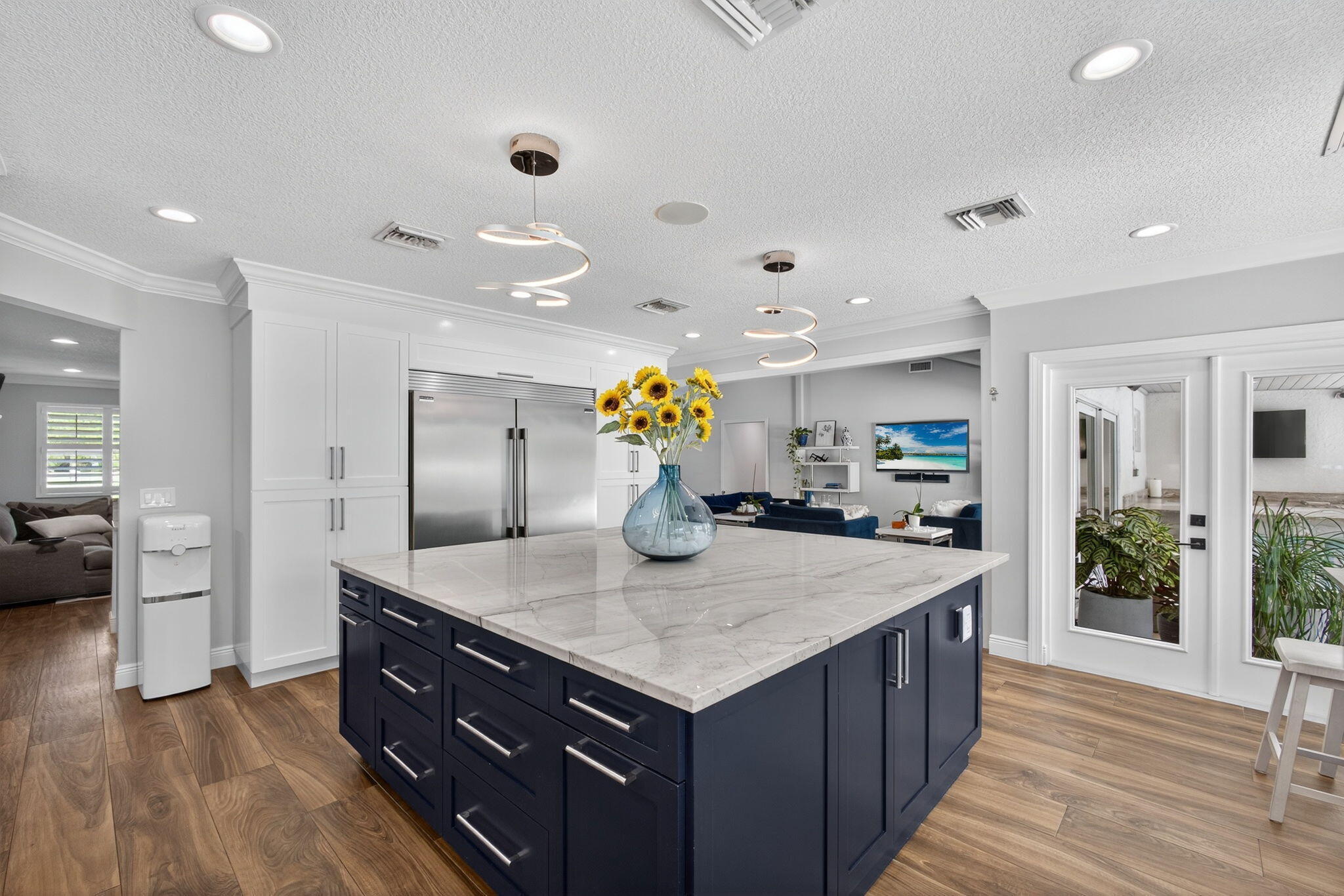 Kitchen featuring a large central island with a stone countertop, navy blue custom cabinetry, stainless steel refrigerator, recessed lighting, and wood-finish flooring