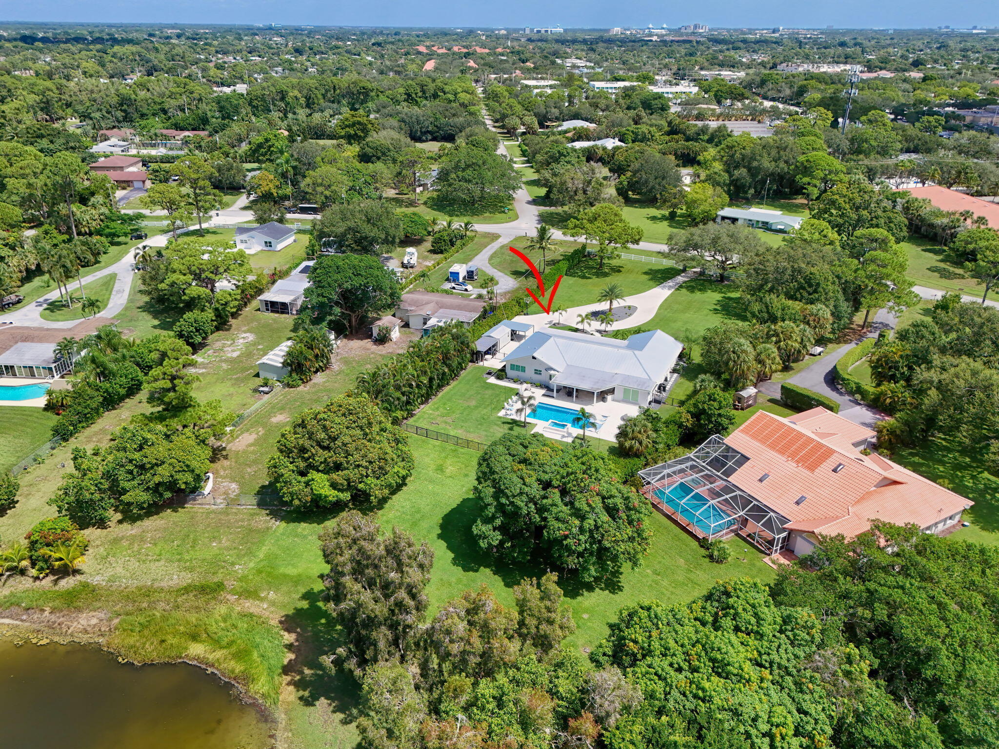 Aerial perspective of a property featuring an expansive lot, a private swimming pool, a patio area, and a circular driveway
