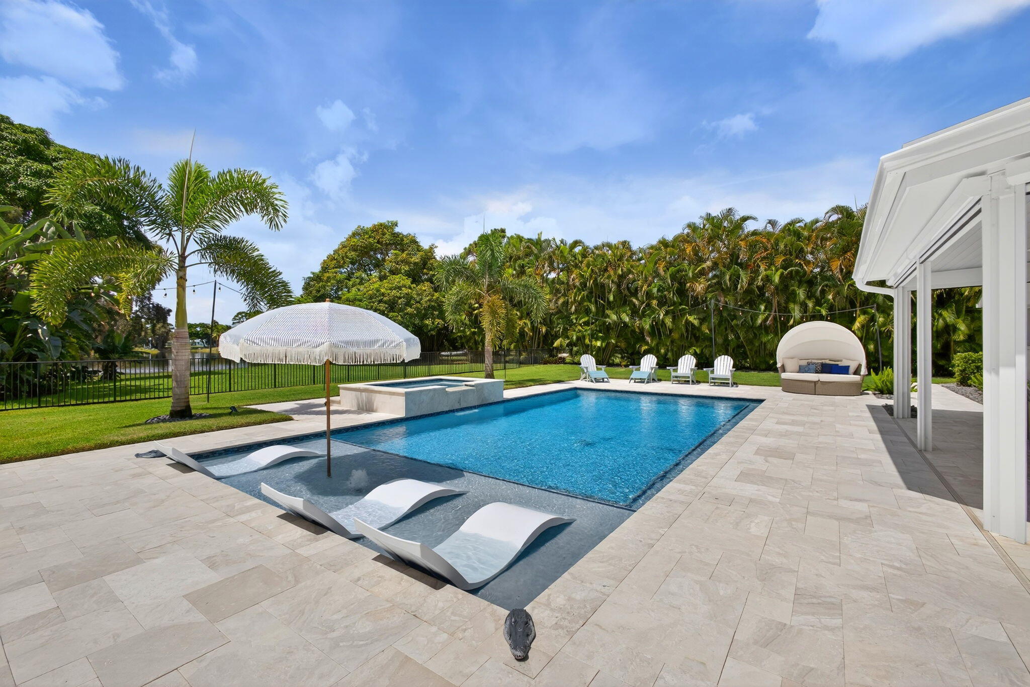 In-ground swimming pool with a Baja shelf, integrated spa, and expansive stone-paver patio