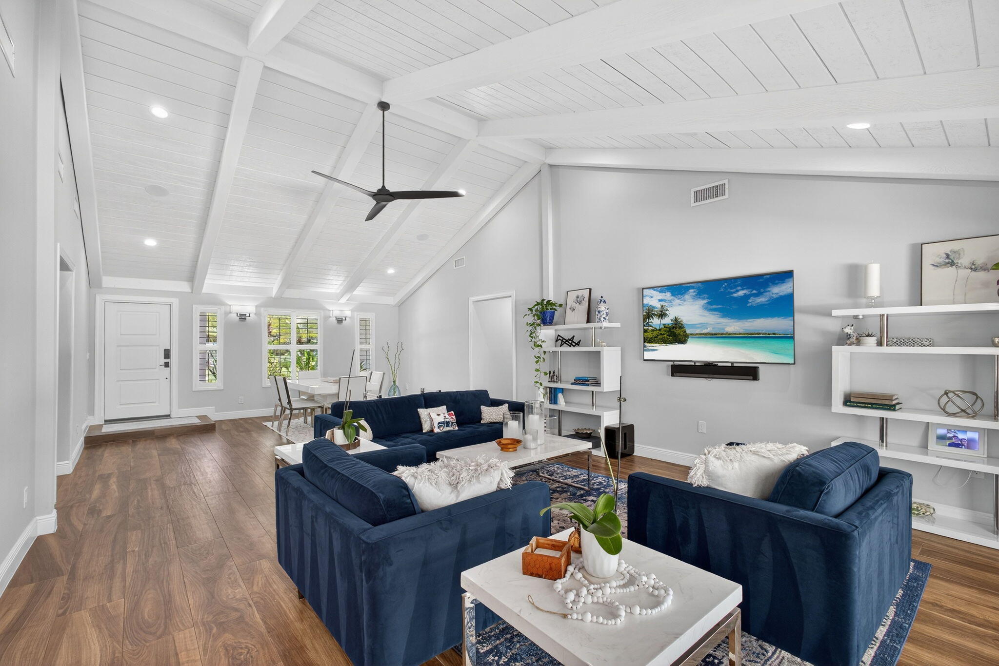 Vaulted ceiling with exposed beams, wood-finish flooring, recessed lighting, and built-in white shelving