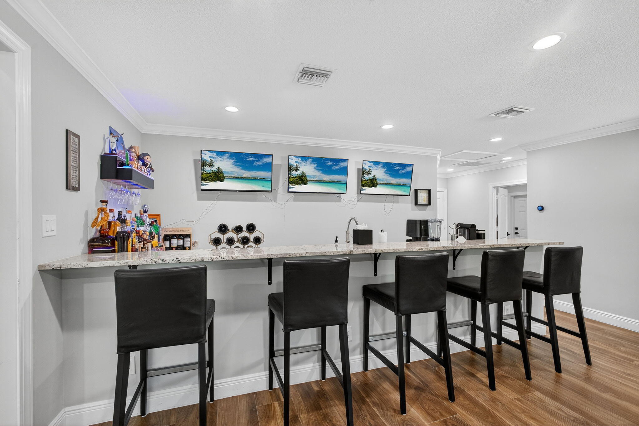 Custom built-in bar area featuring a stone countertop, undermount sink, recessed lighting, and wood-finish flooring