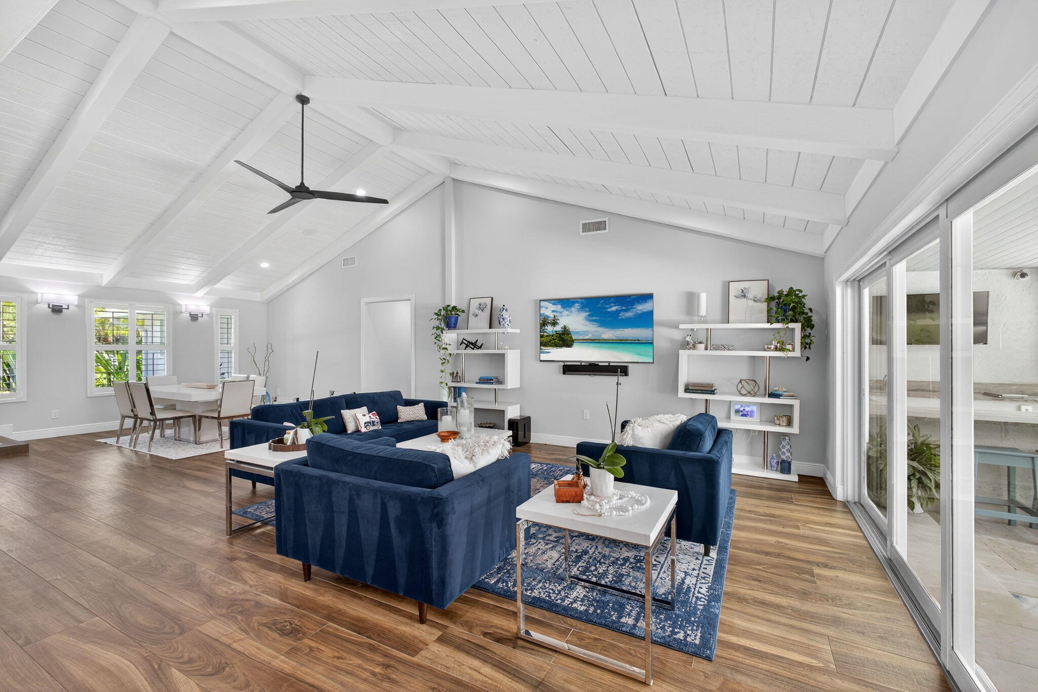 Vaulted ceilings with exposed beams, wood-finish flooring, and sliding glass doors
