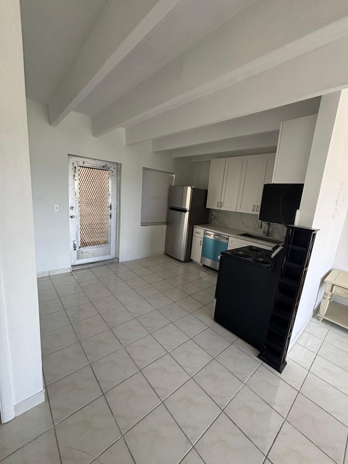 Kitchen featuring white shaker-style cabinetry, stainless steel appliances, tile flooring, and exposed ceiling beams Kitchen featuring white shaker-style cabinetry, stainless steel appliances, tile flooring, and exposed ceiling beams