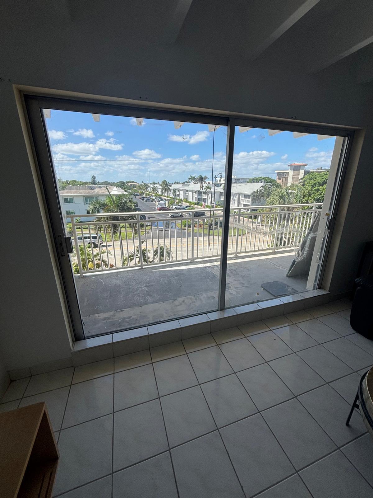 Large sliding glass doors opening to a balcony with metal railings and white tile flooring