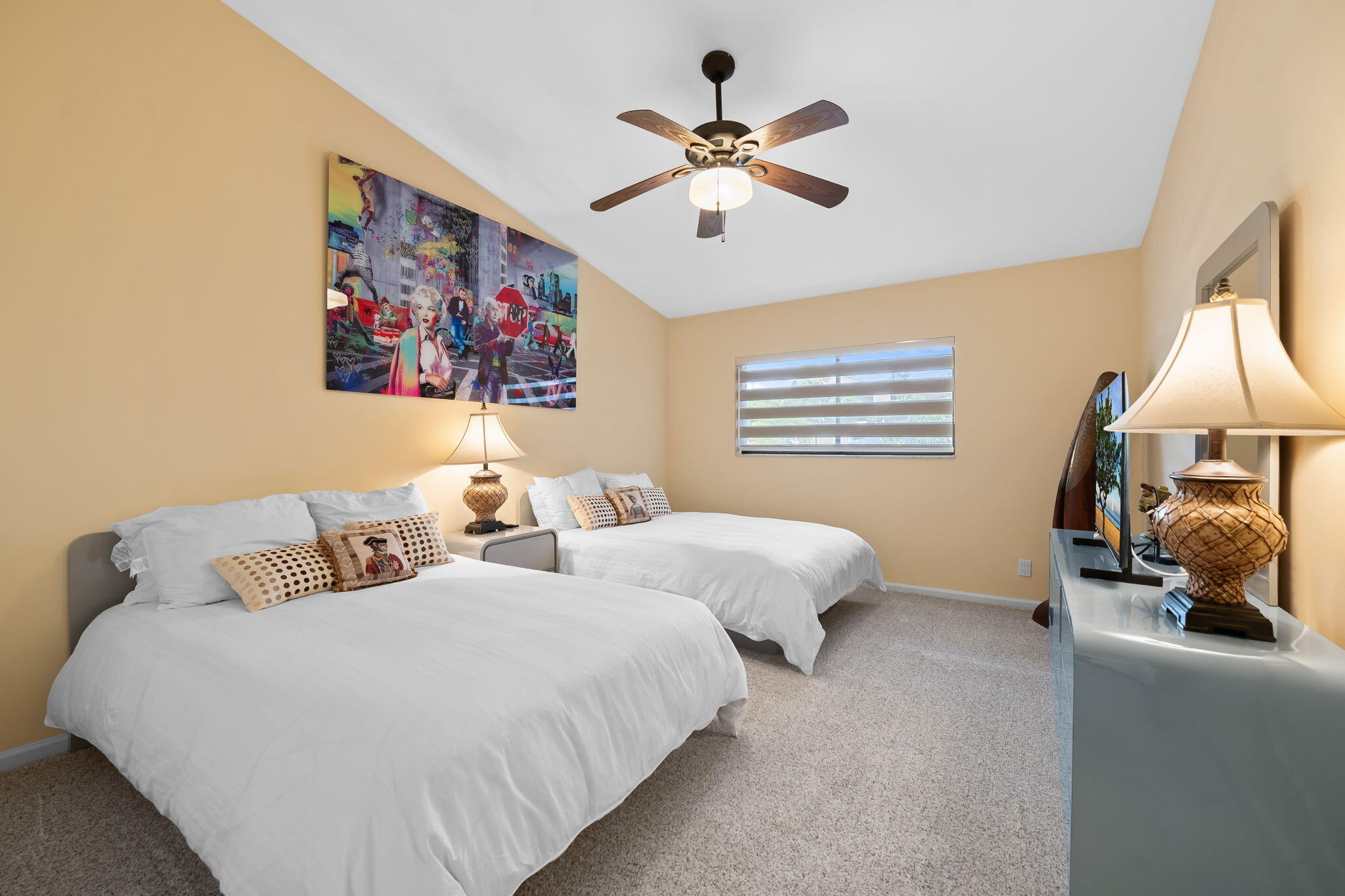 Vaulted ceiling, wall-to-wall carpeting, ceiling fan with integrated lighting, and horizontal window blinds