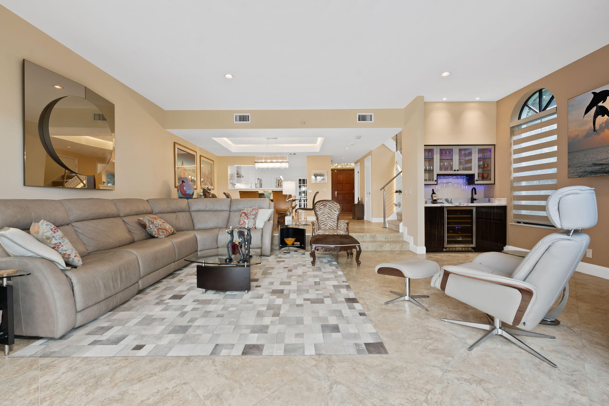 Open-concept living space featuring large format tile flooring, recessed lighting, and a built-in wet bar with cabinetry, stone countertop