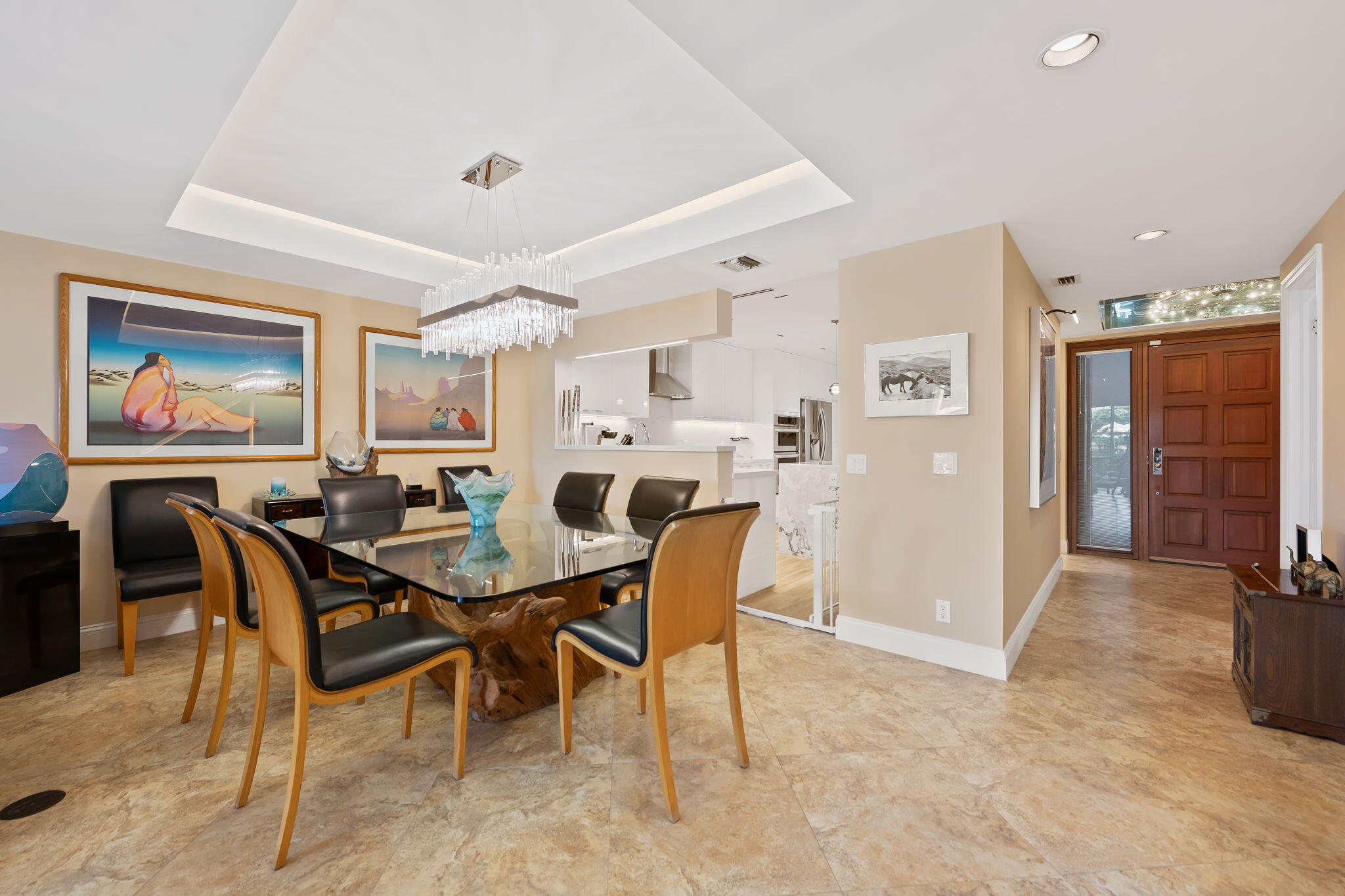 Open-concept interior featuring stone-finish flooring, a recessed tray ceiling, a multi-paneled wood entry door with glass transom