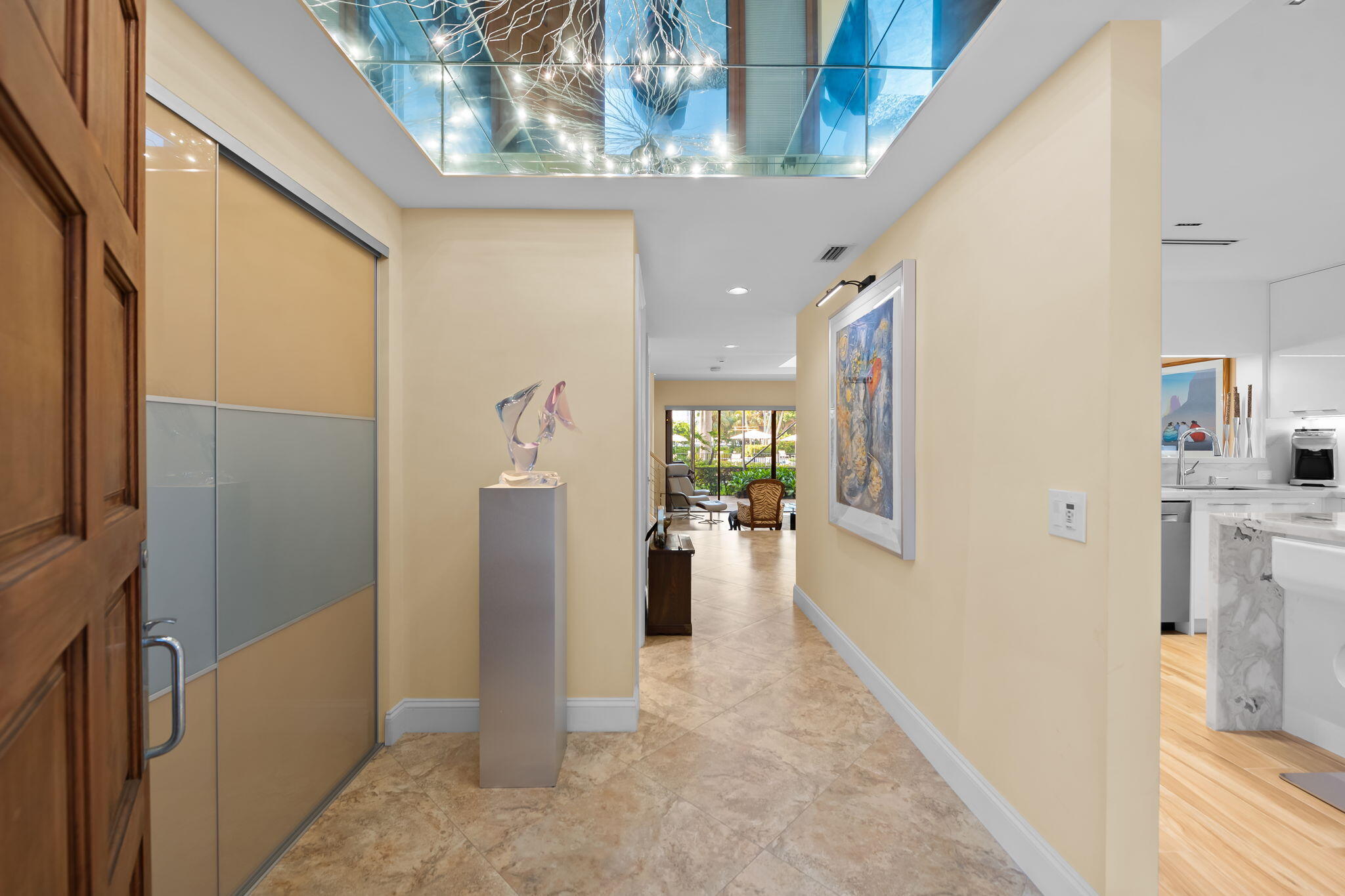 Entryway featuring a beautiful decorative light, recessed lighting, sliding panel doors, and neutral-toned tile flooring