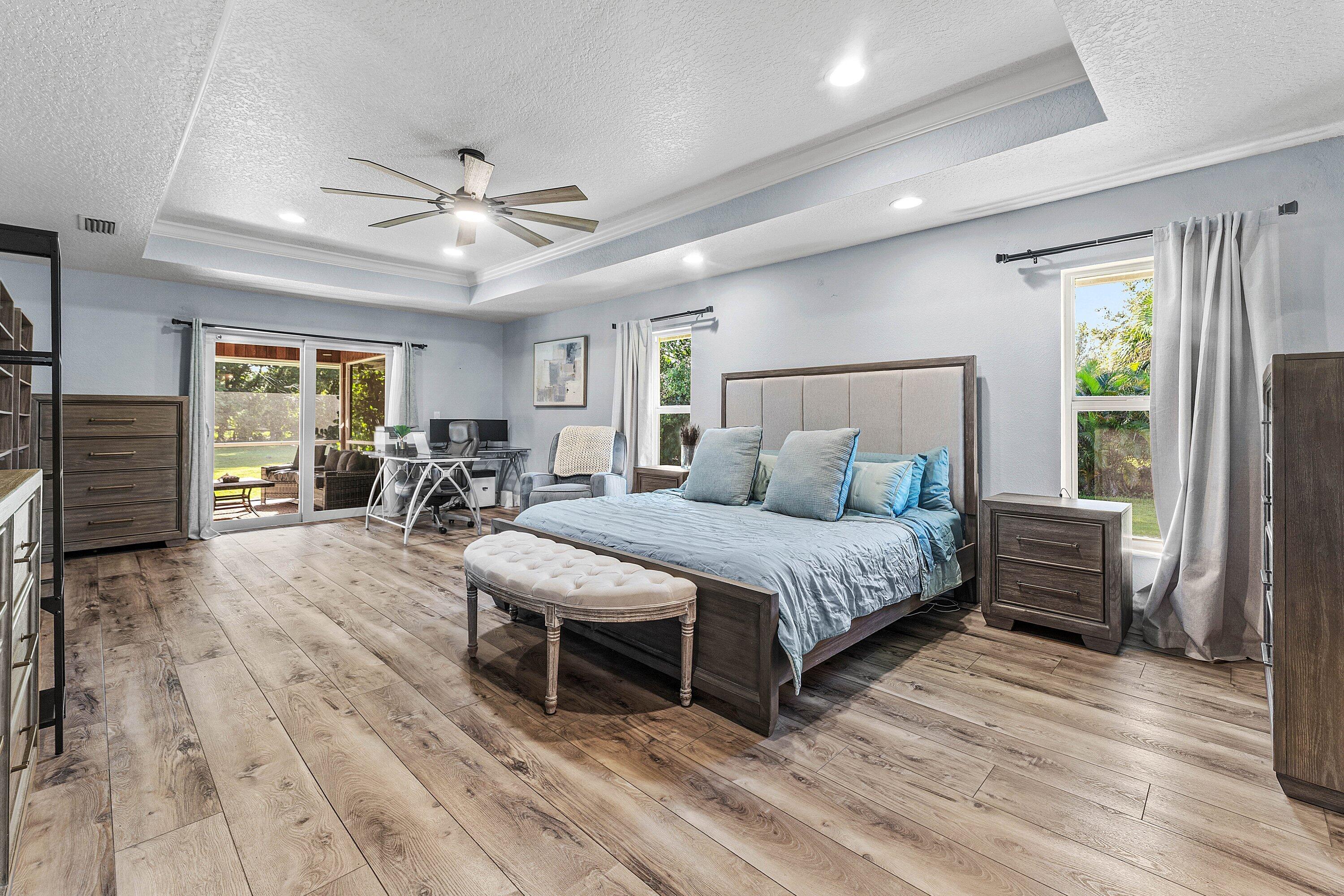 Tray ceiling with recessed lighting, wood-finish flooring, ceiling fan, and sliding glass doors