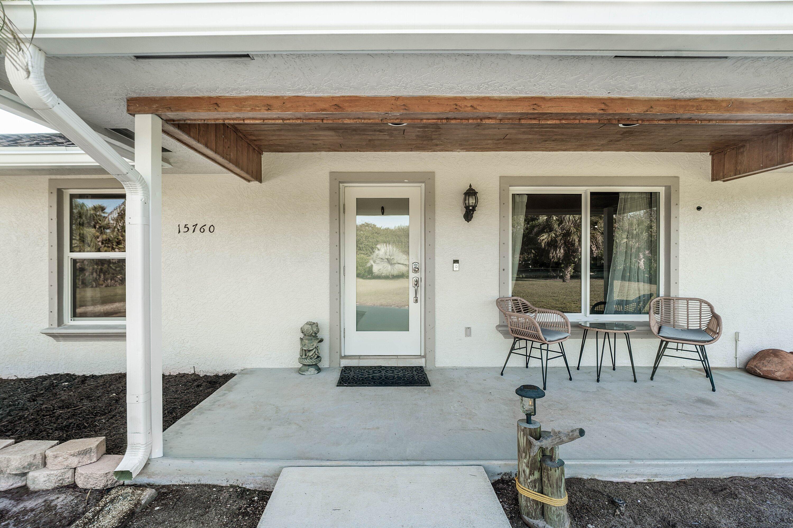Covered front porch featuring a natural wood-finish ceiling, stucco exterior, sliding windows, and a glass-paneled entry door