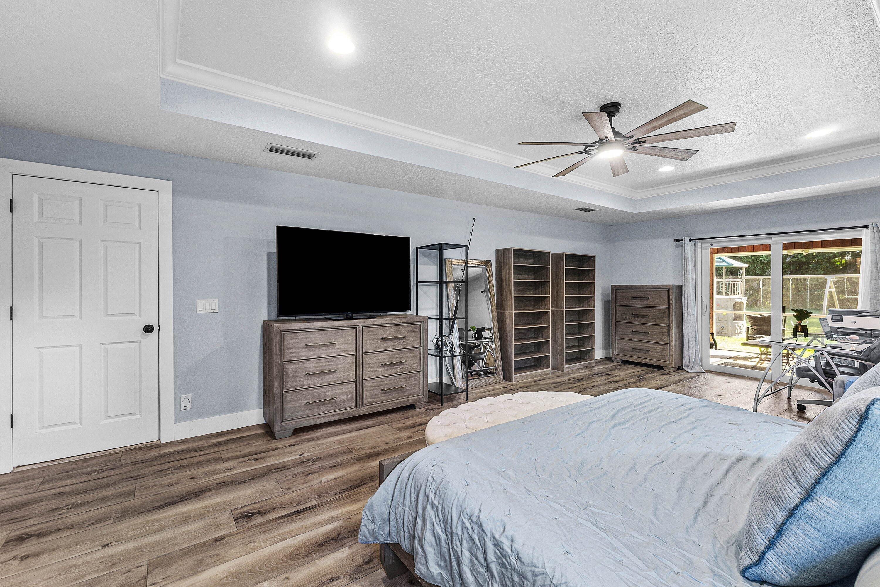 Tray ceiling with recessed lighting, wood-finish flooring, and sliding glass doors providing outdoor access