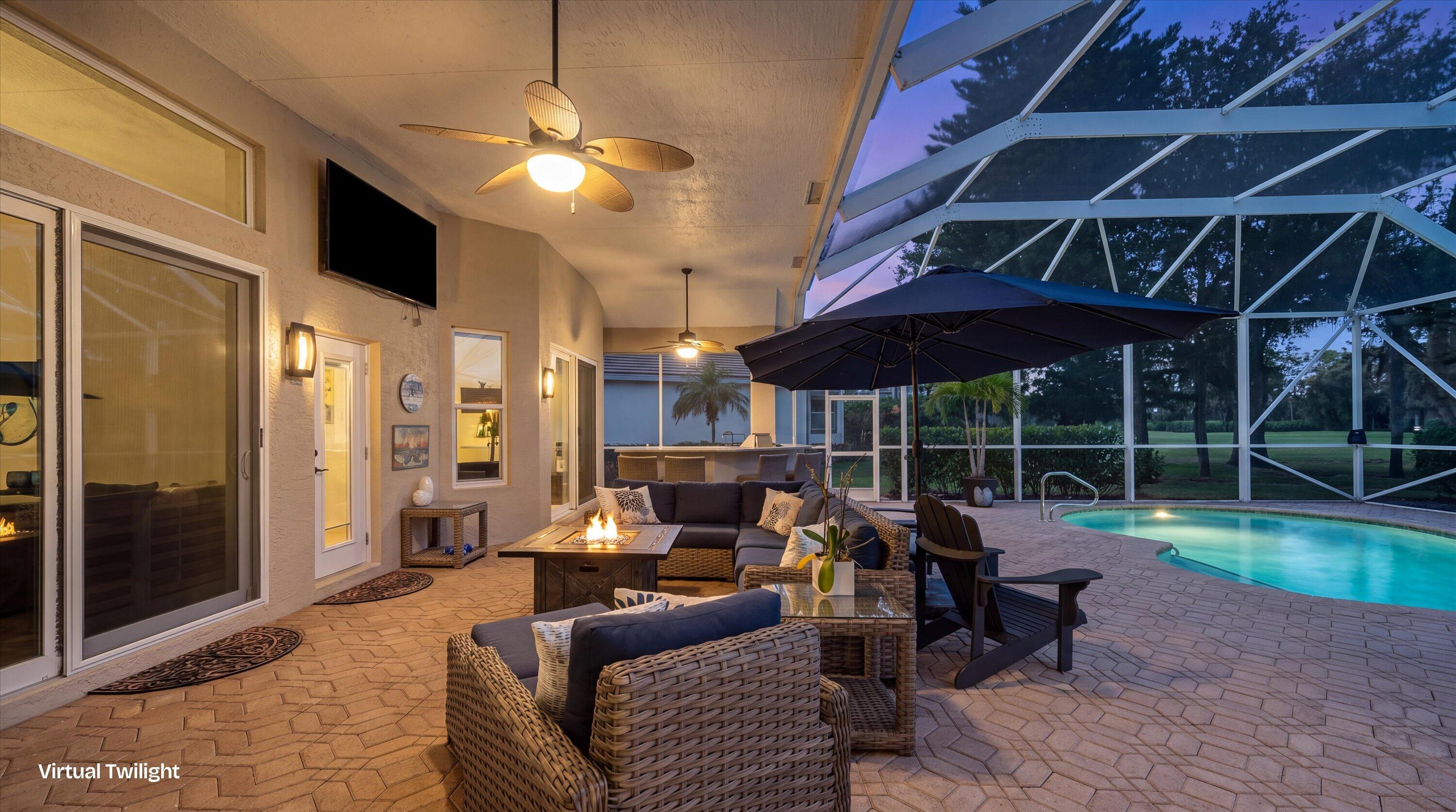 Covered lanai featuring paver flooring, dual ceiling fans, wall-mounted light fixtures, and a screen-enclosed pool