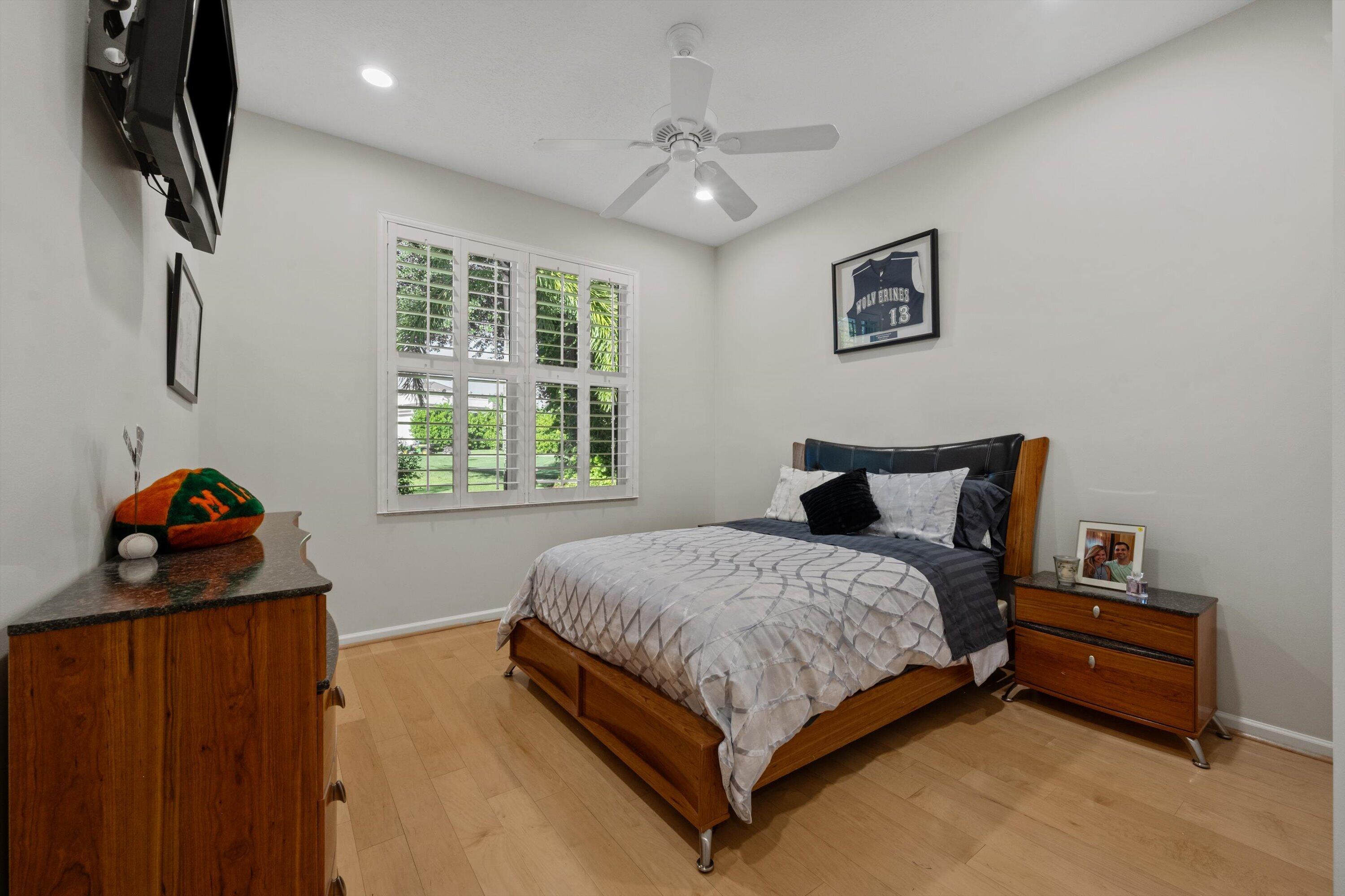 Room featuring wood-finish flooring, plantation shutters, and a ceiling fan with integrated lighting