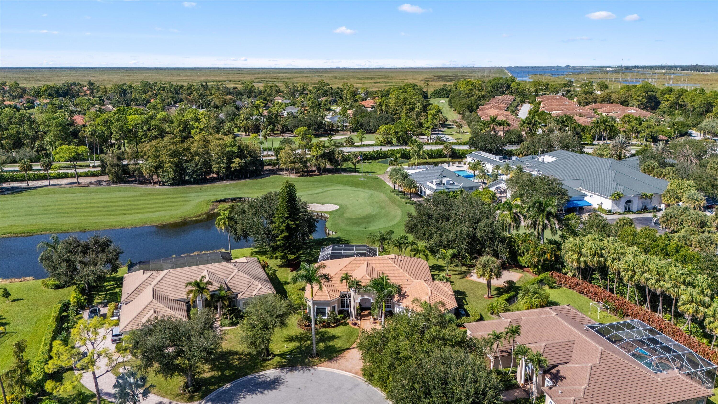 Aerial perspective of a residential property featuring tile roof construction, a screened-in lanai, and landscaped grounds situated on a golf course