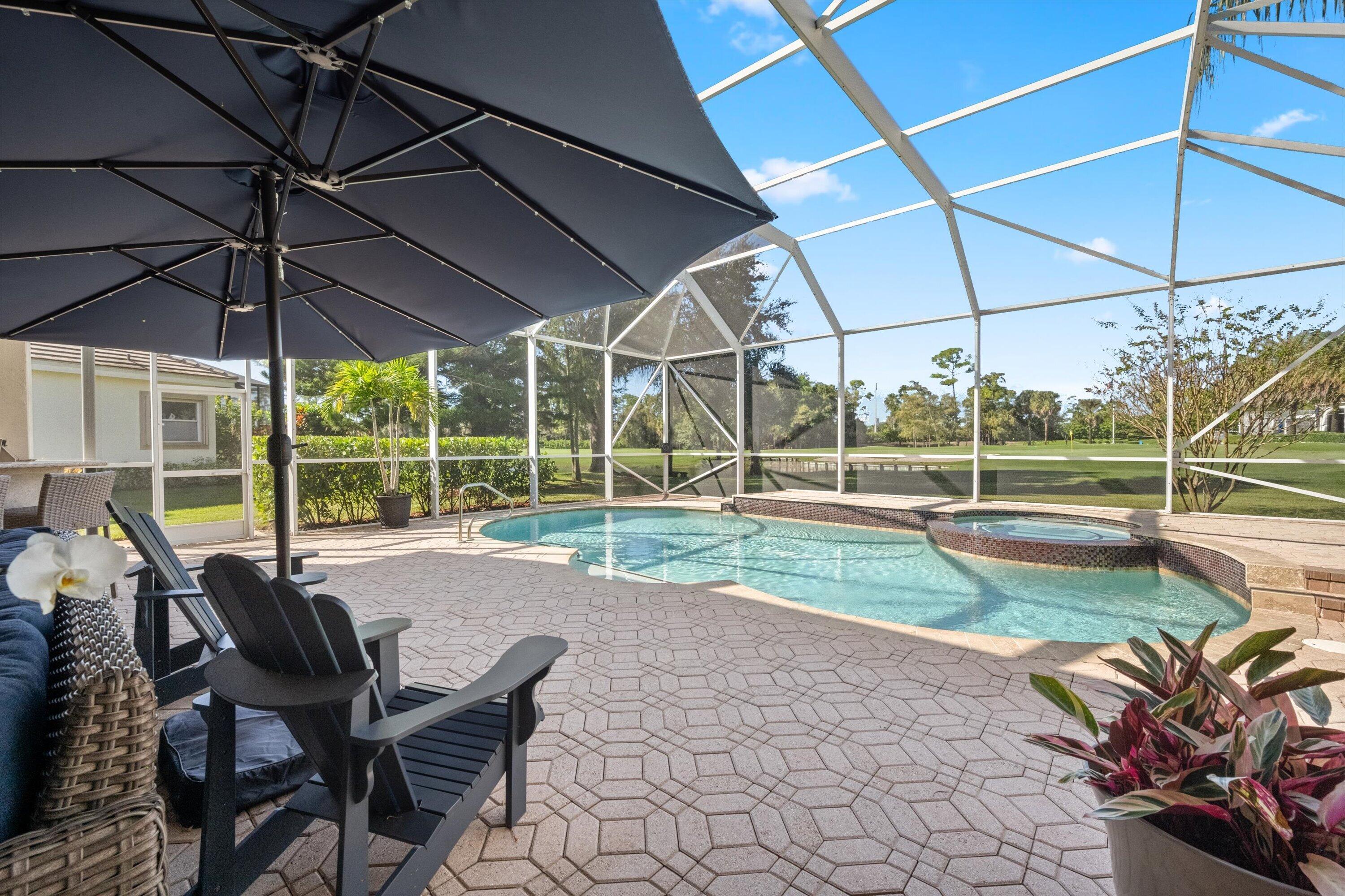 Screened-in pool area featuring a built-in spa, paver patio, and metal enclosure