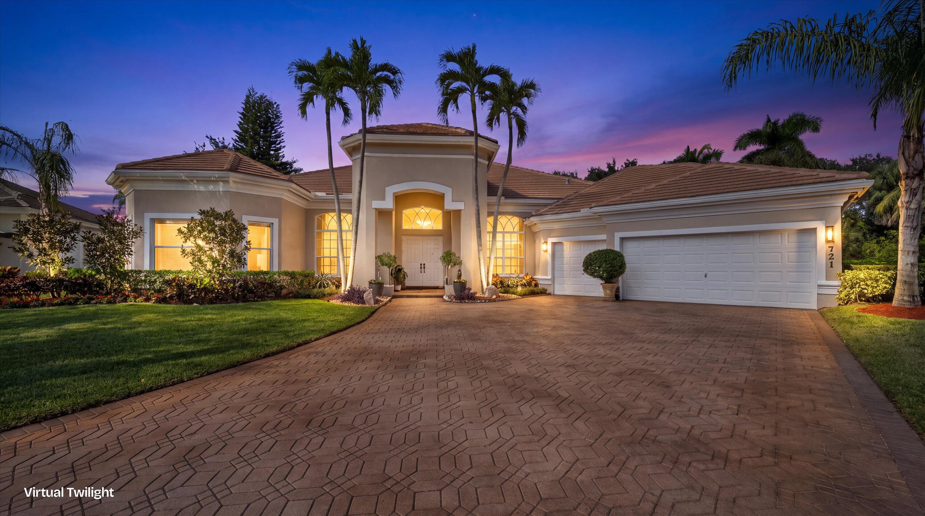 Stucco exterior featuring a tiled roof, arched entryway, paved driveway, and established palm trees Stucco exterior featuring a tiled roof, arched entryway, paved driveway, and established palm trees