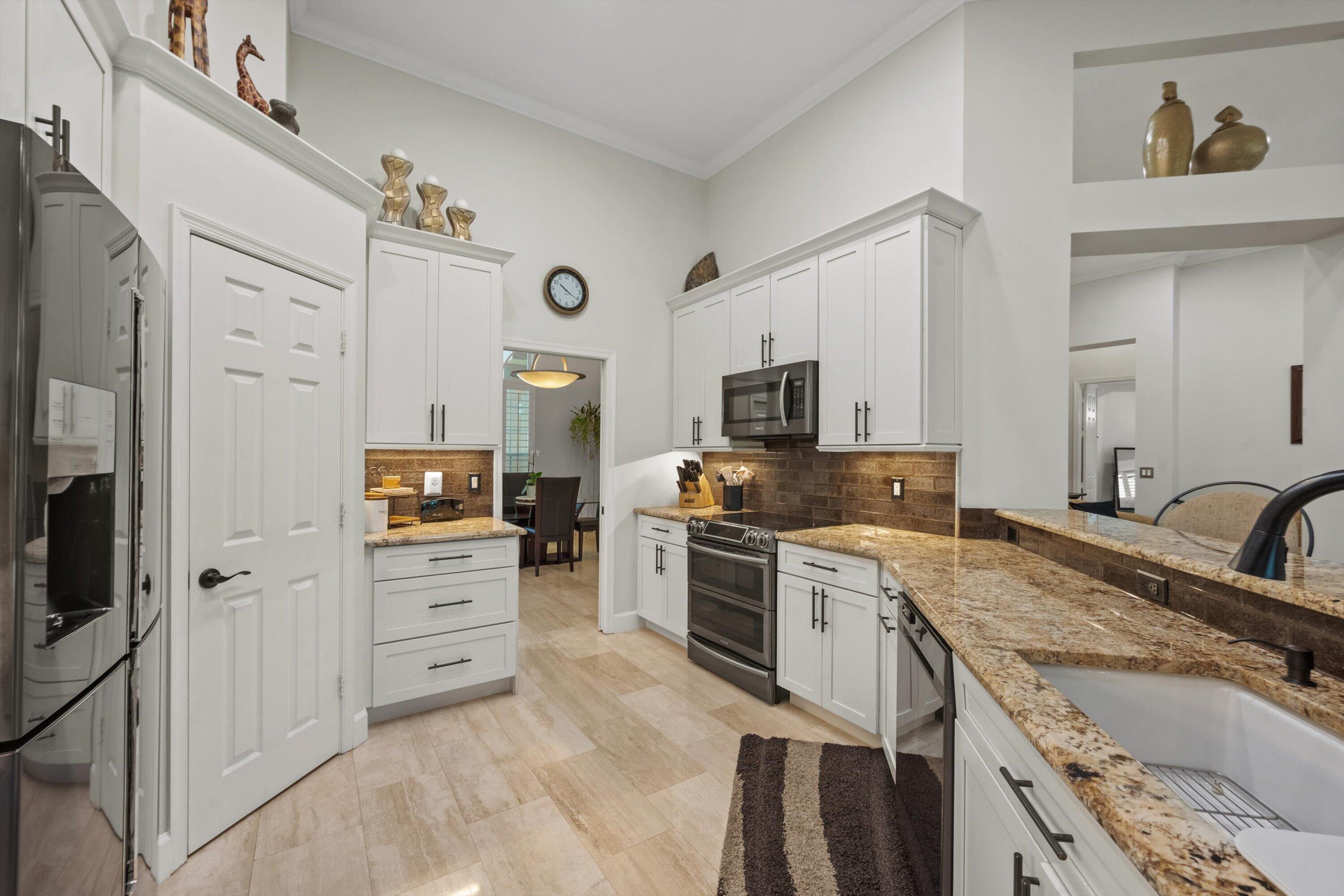 Kitchen featuring white cabinetry, stone countertops, a farmhouse-style sink, tiled backsplash, and stone-finish flooring