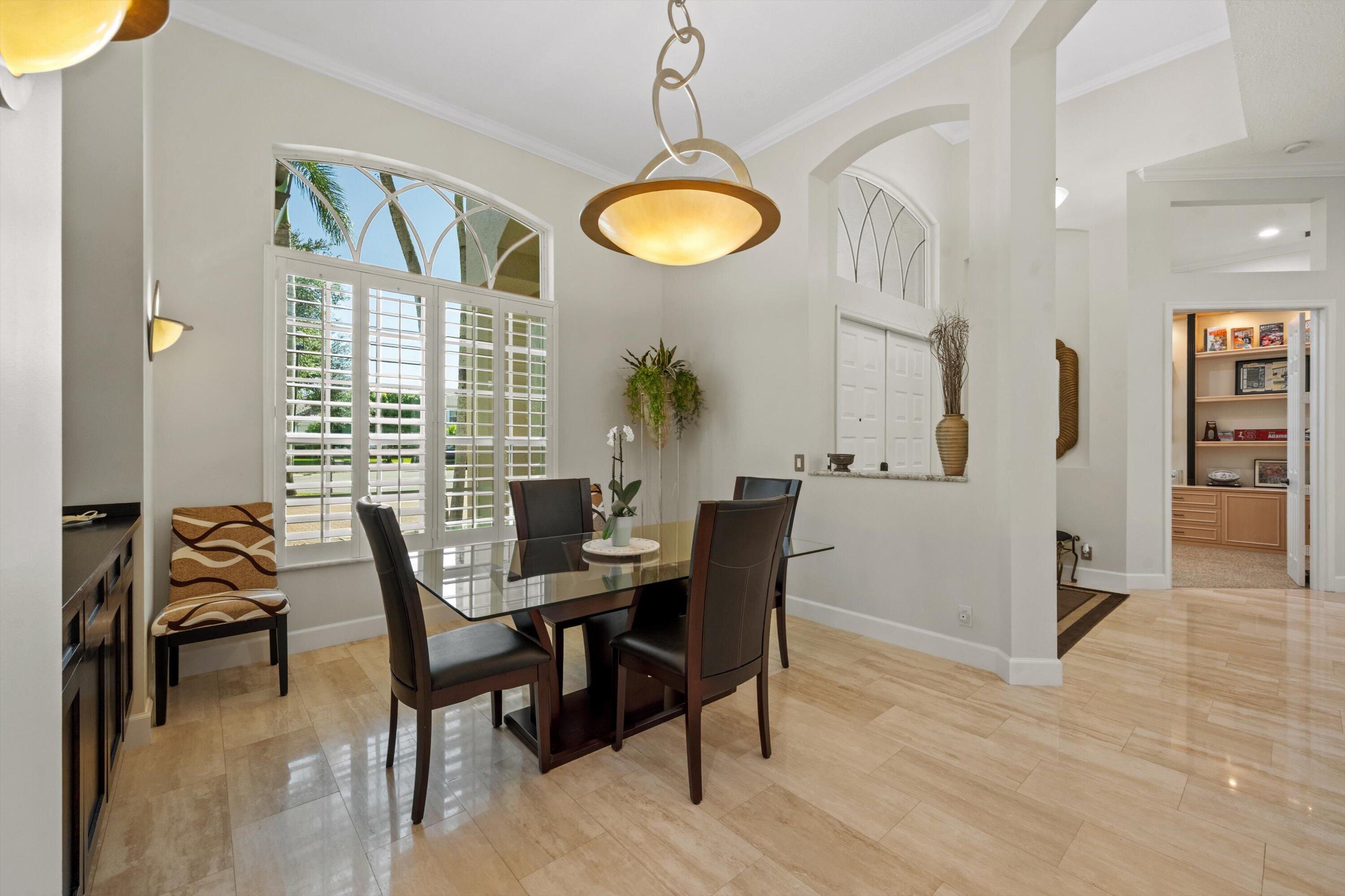Polished stone flooring, arched windows with plantation shutters, vaulted ceilings, and a decorative multi-tier pendant light fixture