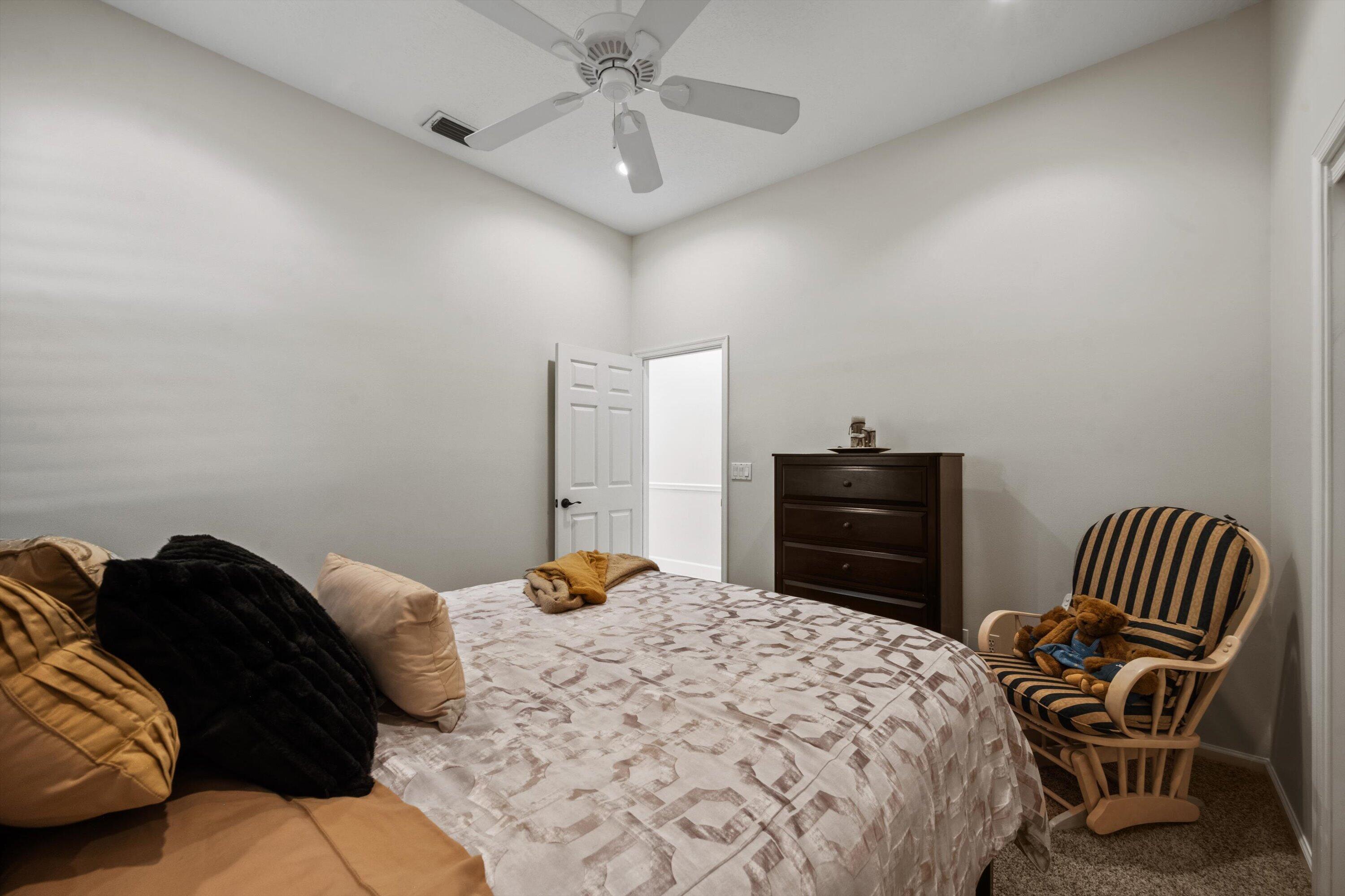 High ceilings, carpeted flooring, and a central ceiling fan with integrated light fixture