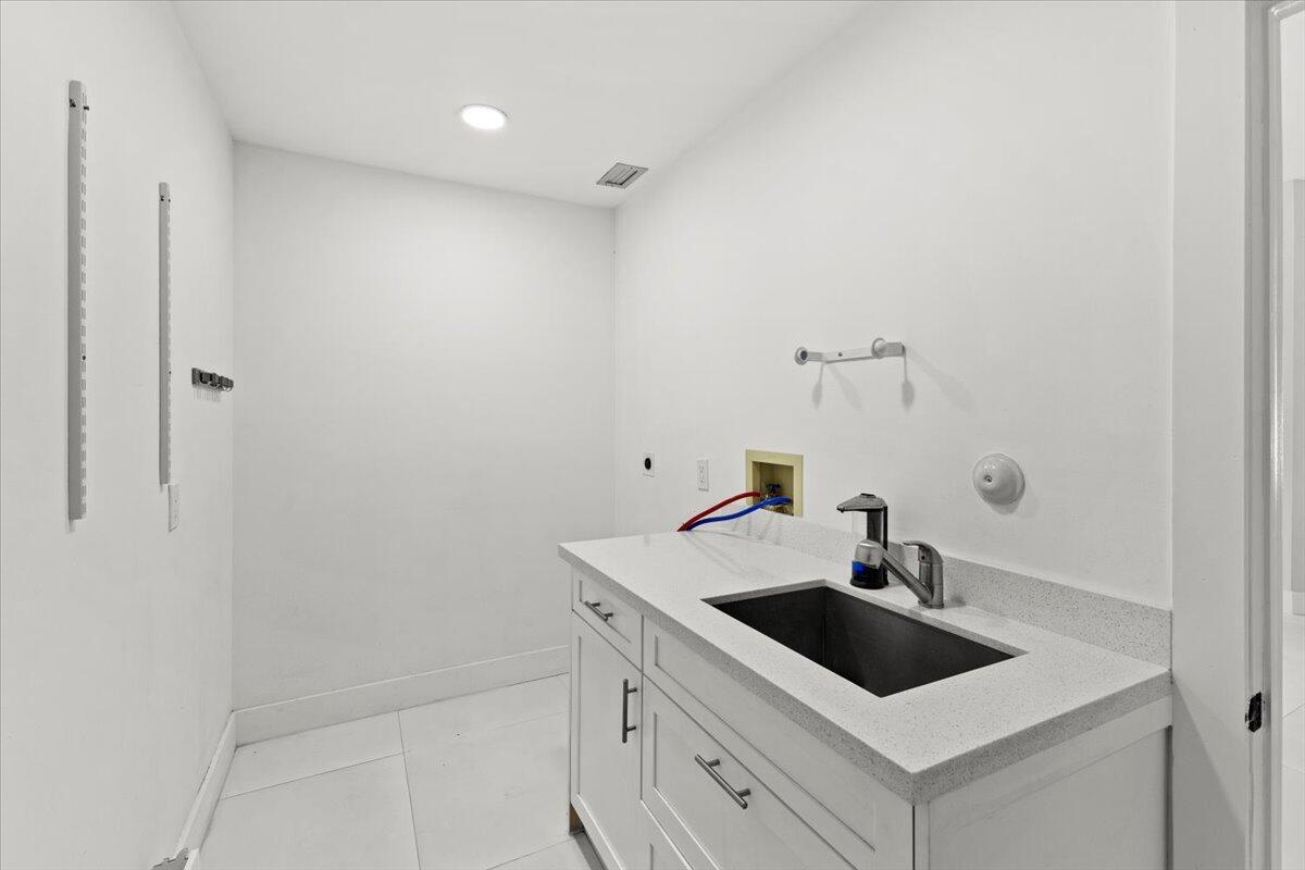 Laundry room featuring washer and dryer hookups, a utility sink, and convenient under sink drawer storage.