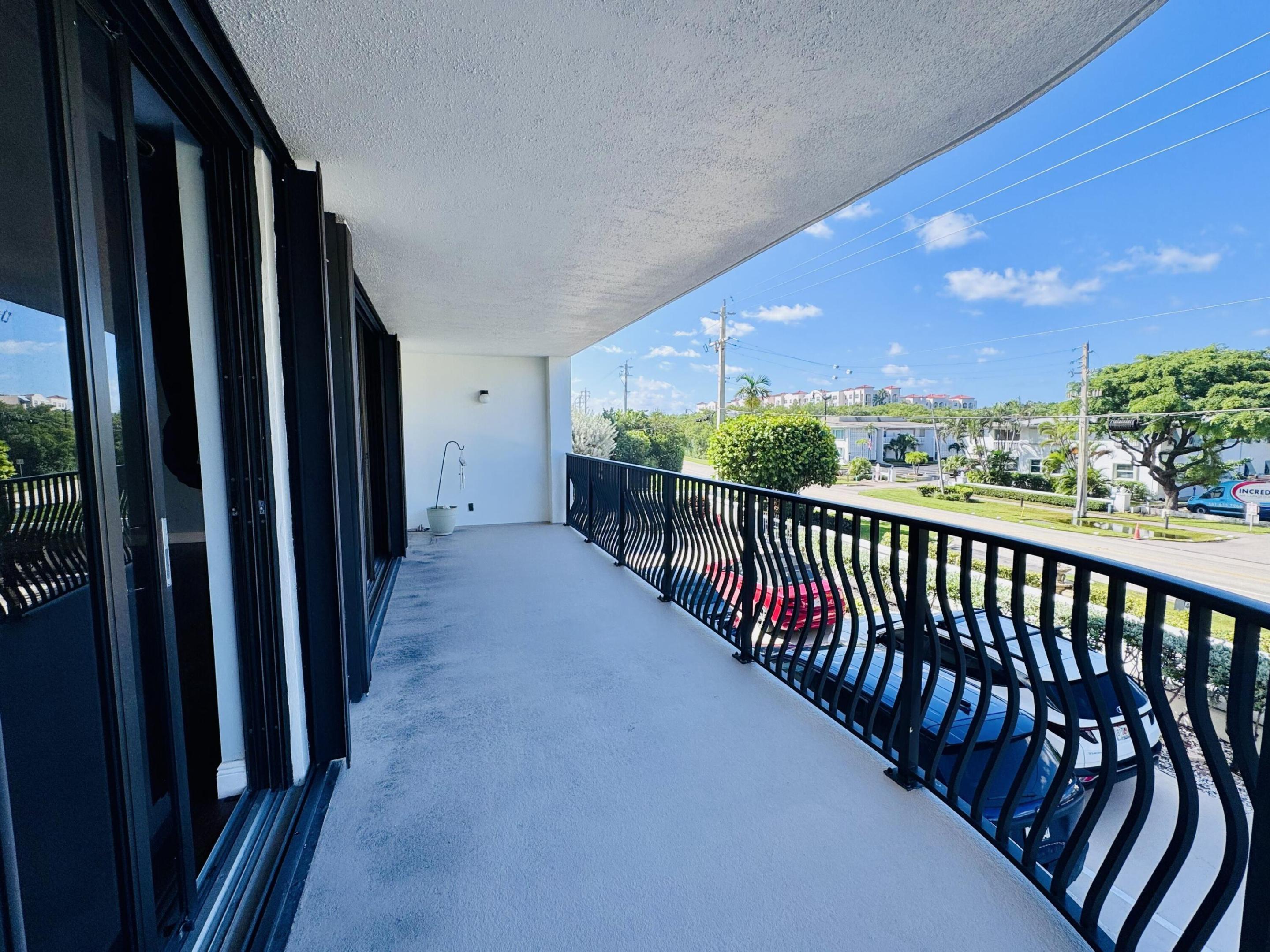 Covered balcony featuring a textured concrete surface and black metal serpentine railings