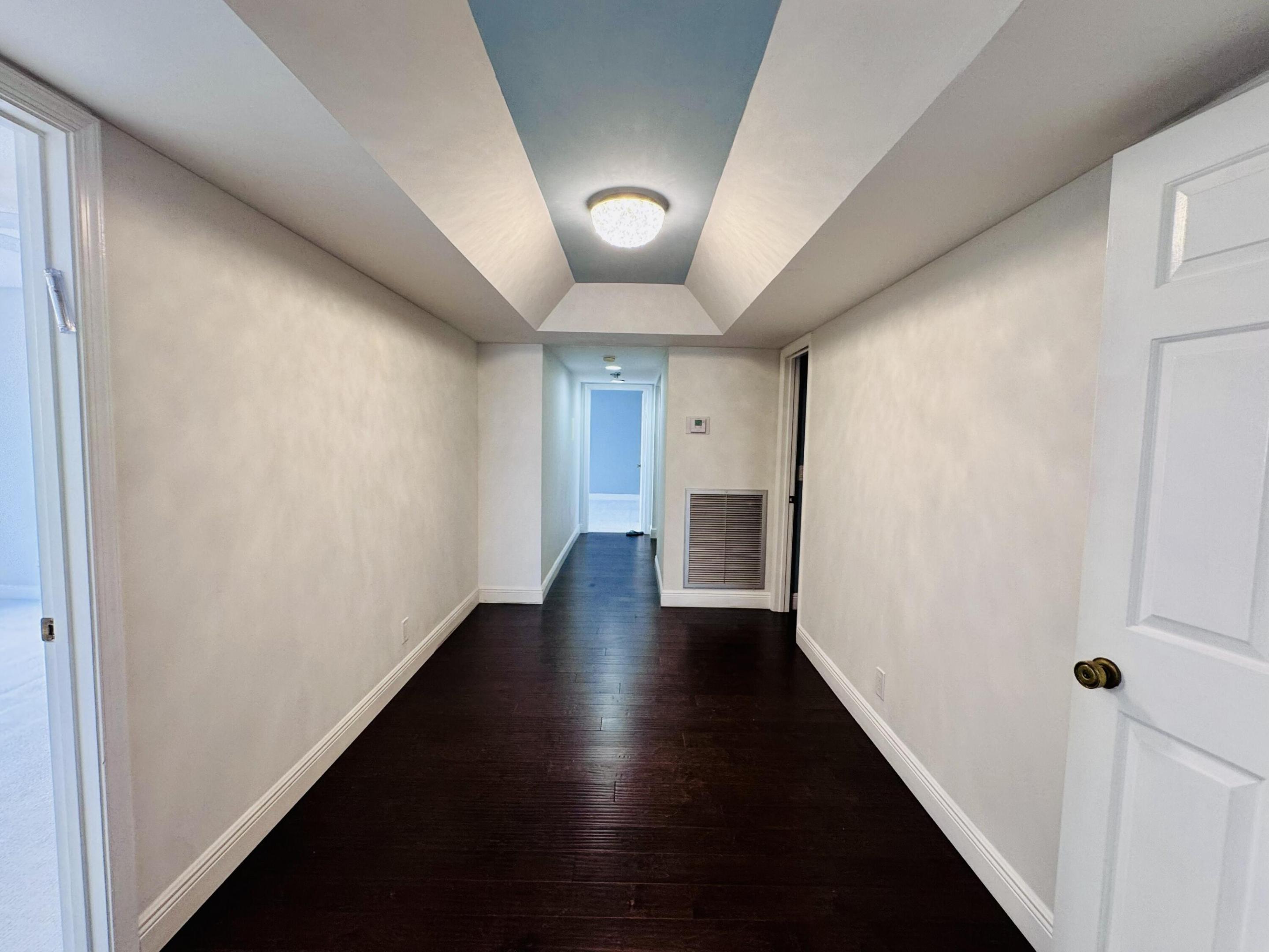 Tray ceiling with accent color, dark wood-finish flooring, and flush-mount lighting fixture Tray ceiling with accent color, dark wood-finish flooring, and flush-mount lighting fixture