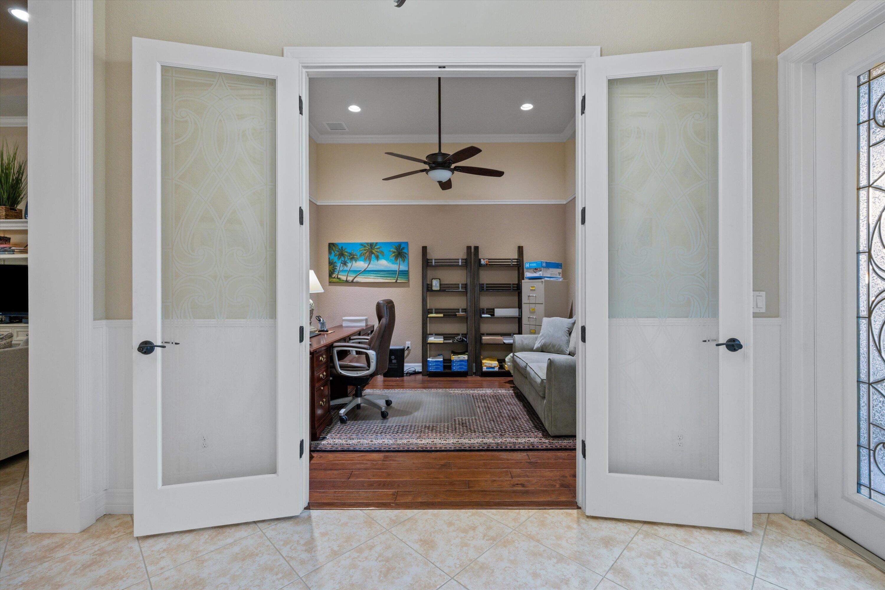 French-style double doors featuring frosted glass panels and dark hardware, wood-finish flooring, recessed lighting, and a ceiling fan