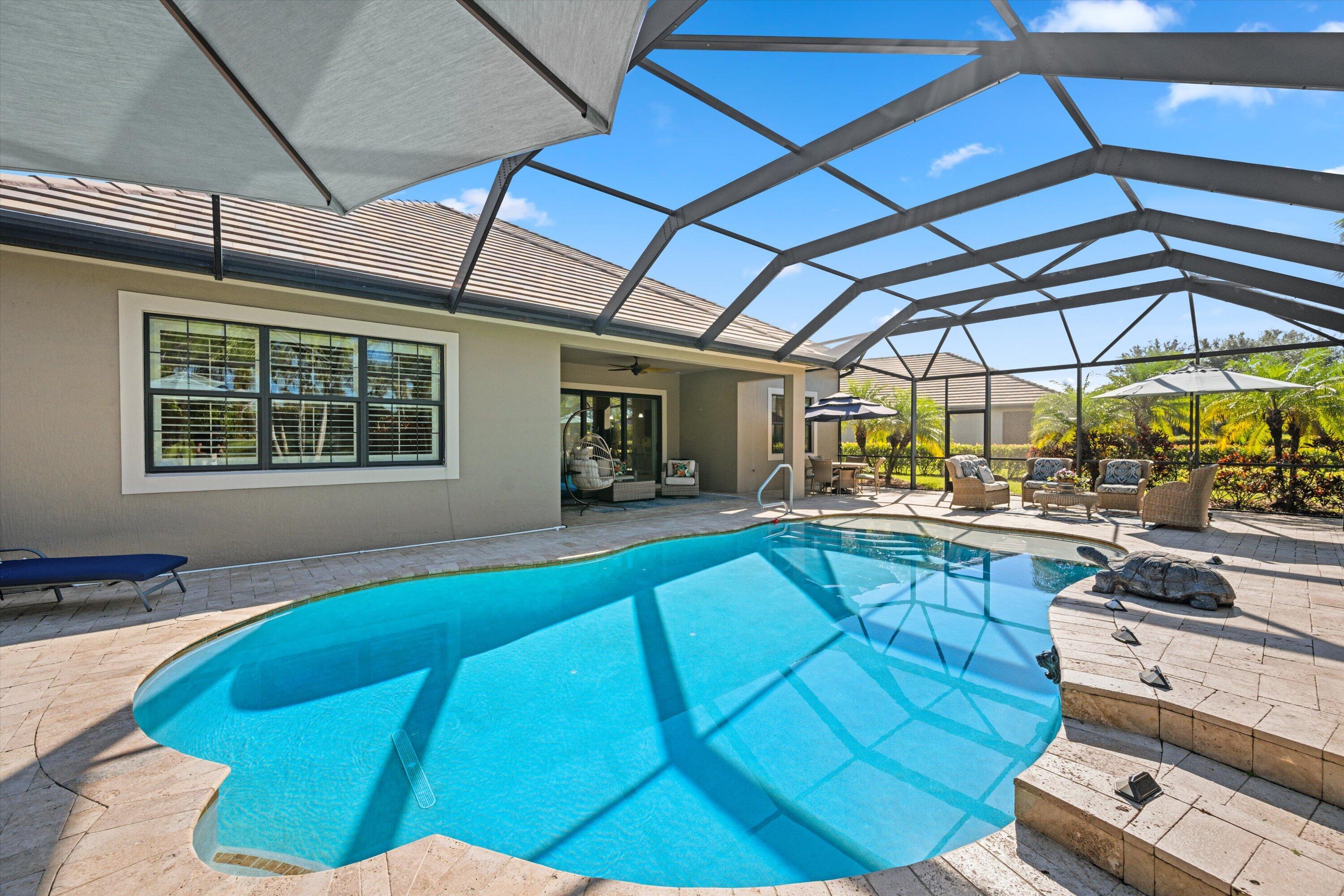 Screened-in pool area featuring a paver deck, integrated step entry, and a covered lanai