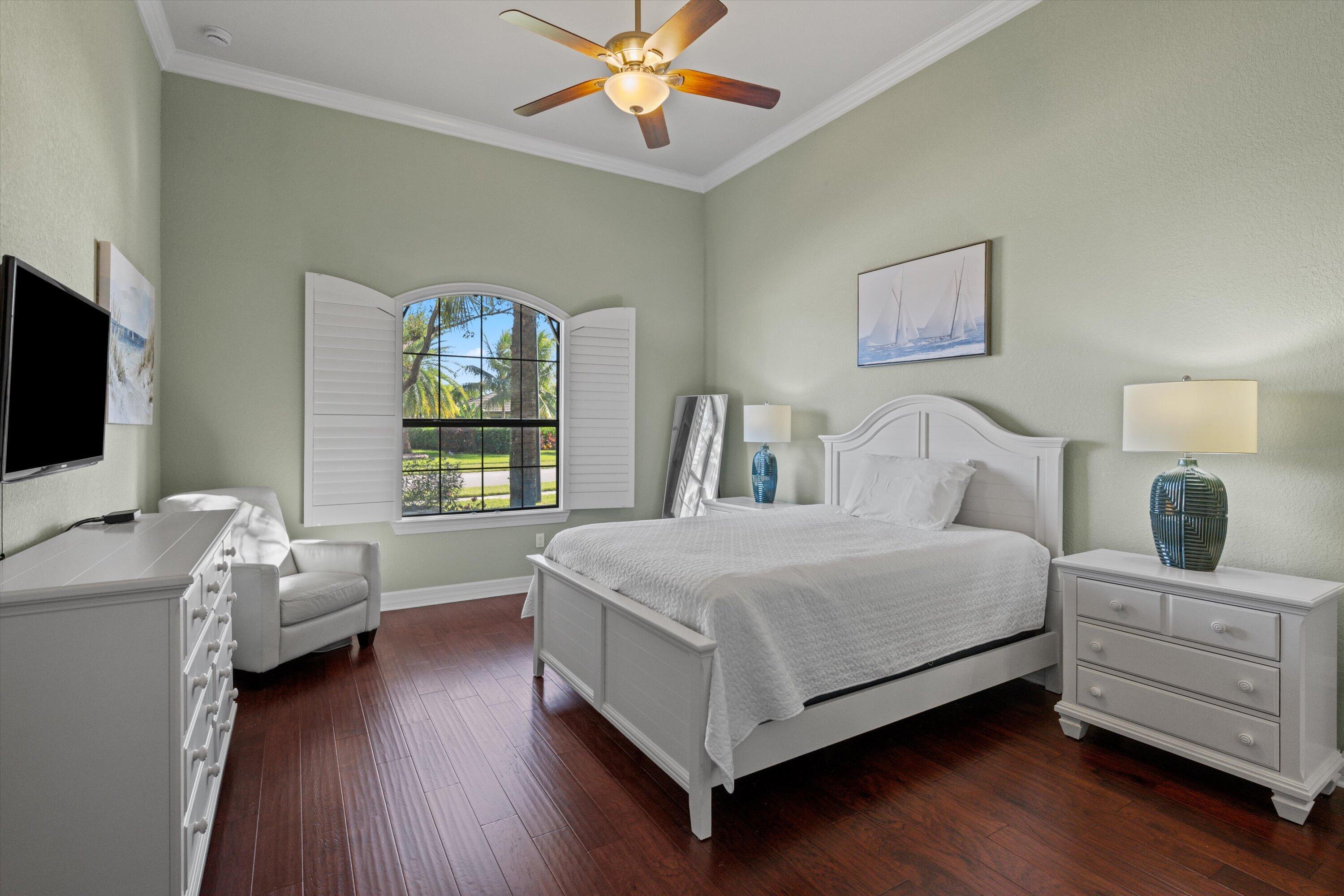 High ceilings with crown molding, wood-finish flooring, and an arched window featuring plantation shutters