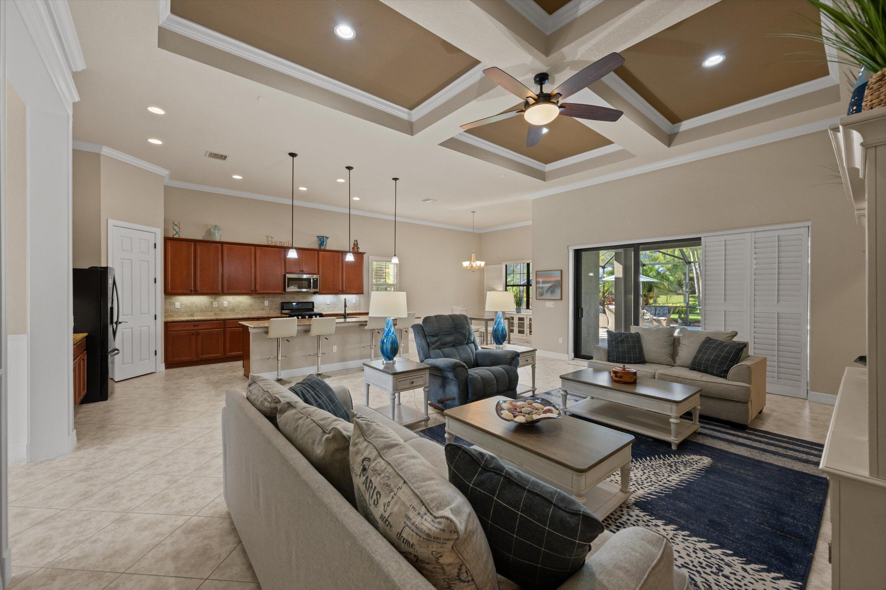 Open-concept interior featuring a coffered ceiling, recessed lighting, tile flooring, and custom cabinetry with an integrated breakfast bar Open-concept interior featuring a coffered ceiling, recessed lighting, tile flooring, and custom cabinetry with an integrated breakfast bar