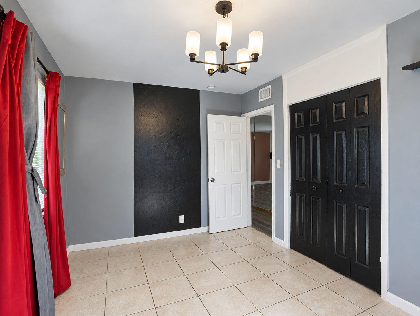 Ceramic tile flooring, five-light chandelier with frosted glass shades, and black six-panel closet doors