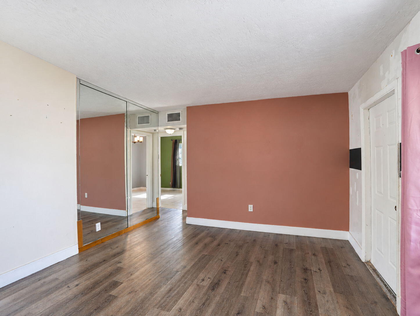 Living Room featuring wood-finish flooring, floor-to-ceiling mirrored wall paneling