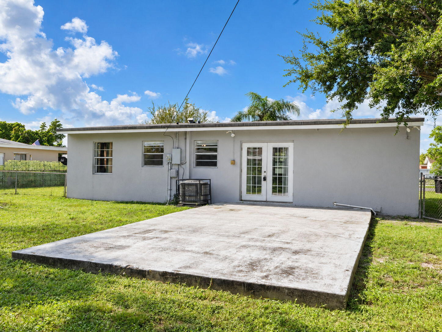 Rear exterior featuring a concrete patio and a chain-link fenced perimeter