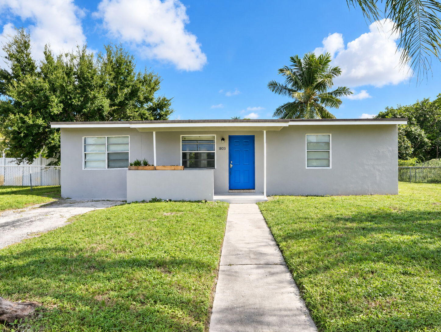 Single-story exterior featuring a neutral stucco facade, bright blue front door, covered front entryway, and concrete walkway